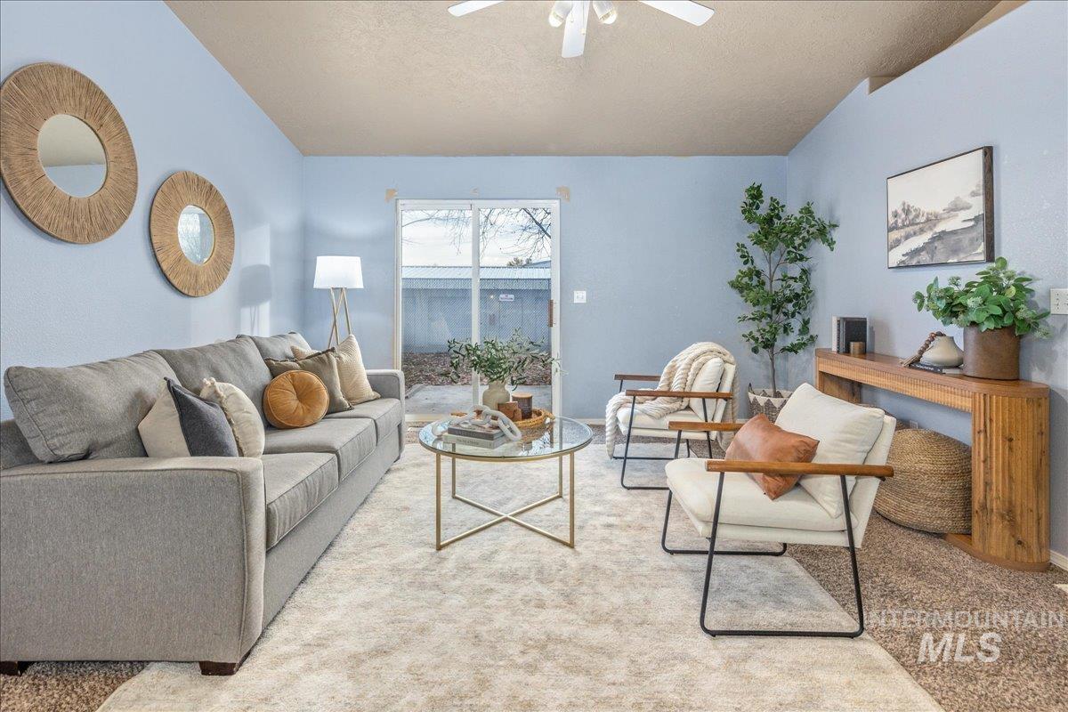 Living room featuring a textured ceiling, carpet floors, and a ceiling fan