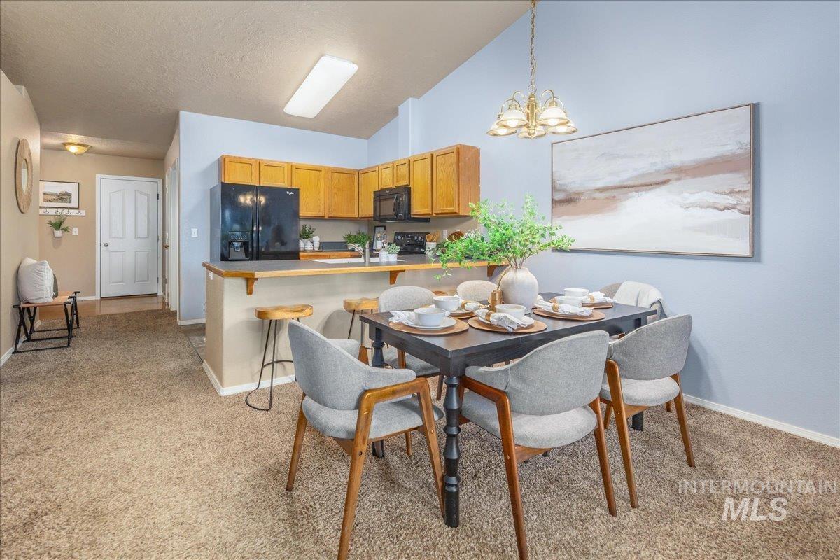 Dining room with light carpet, a chandelier, a textured ceiling, and high vaulted ceiling