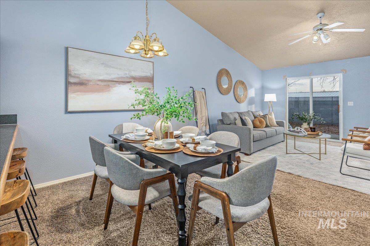 Carpeted dining space featuring lofted ceiling, ceiling fan, and a chandelier