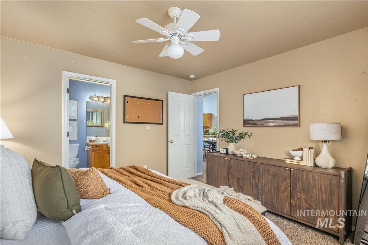 Bedroom with carpet floors, connected bathroom, and a ceiling fan