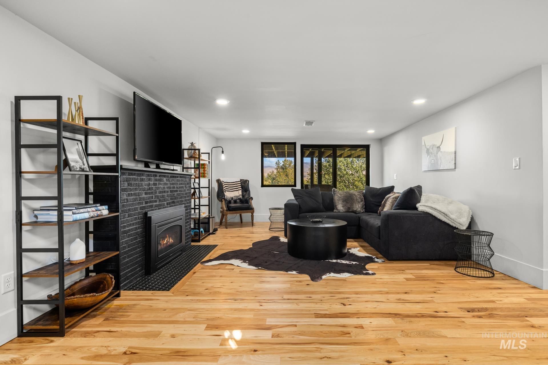 Living area with light wood-type flooring, recessed lighting, and a tiled fireplace