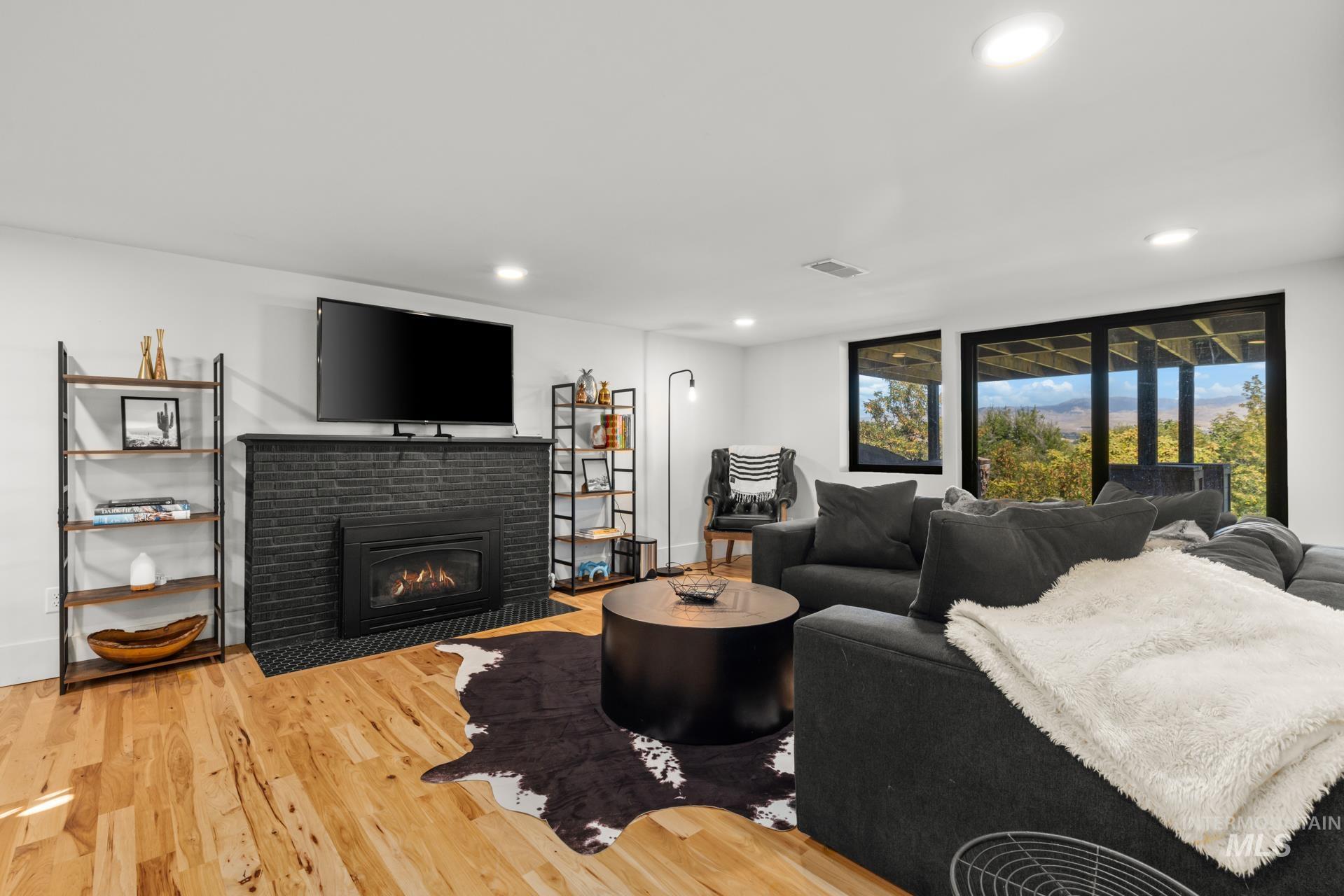 Living area featuring light wood-style flooring, a brick fireplace, and recessed lighting