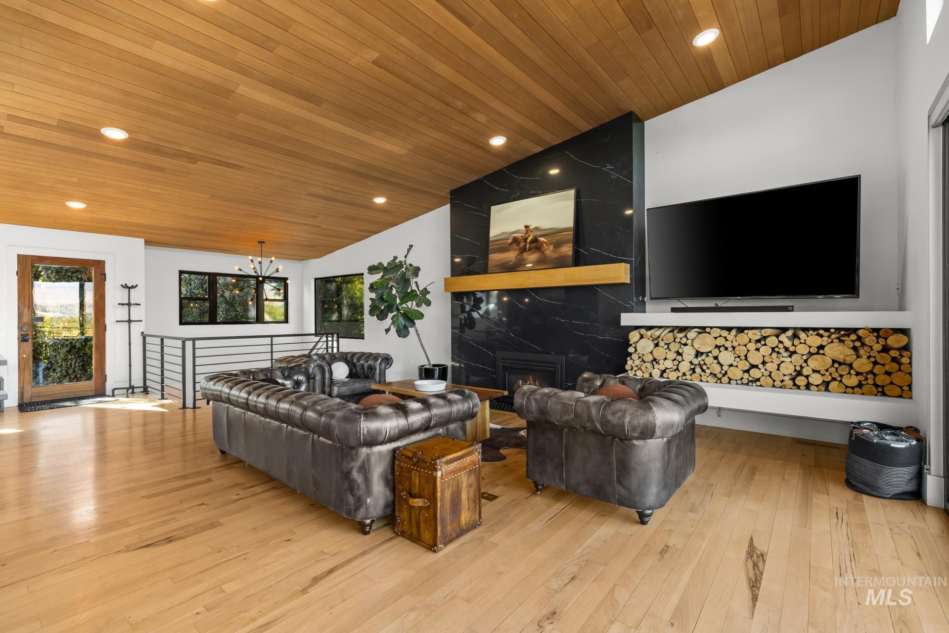 Living area featuring recessed lighting, wood ceiling, light wood-style flooring, a chandelier, and a high end fireplace
