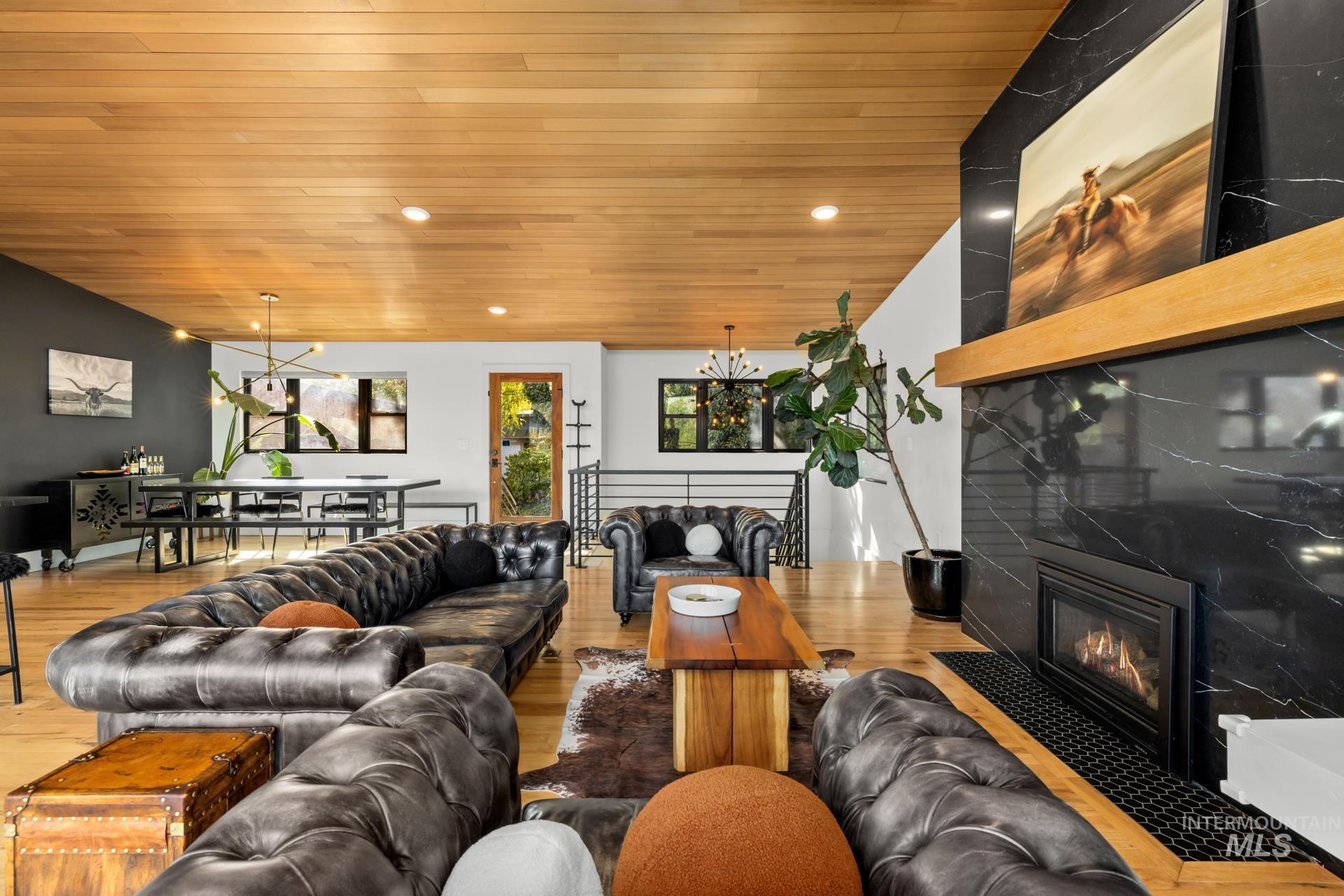 Living area featuring a fireplace, wood ceiling, wood finished floors, recessed lighting, and a chandelier