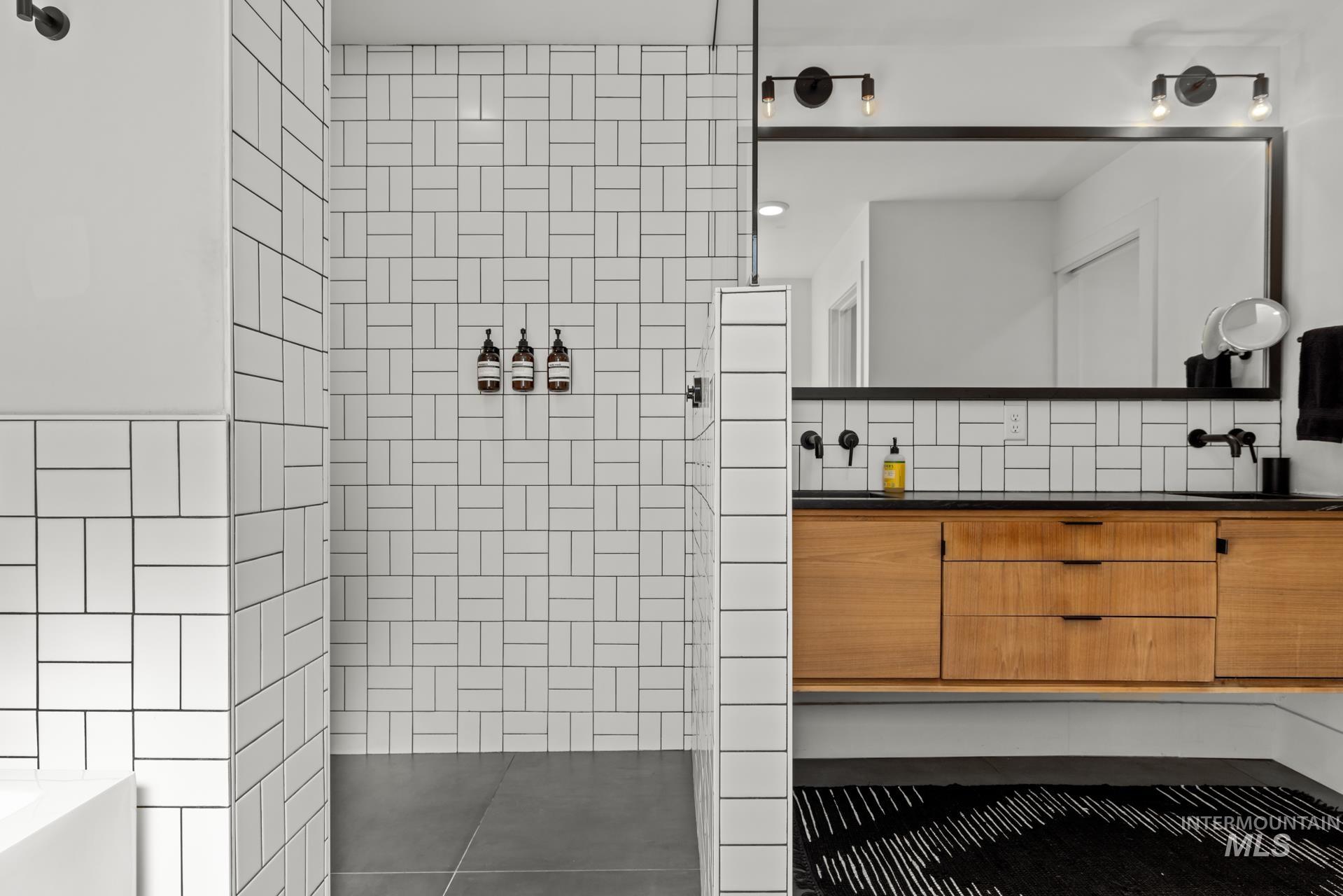 Bathroom with a walk in shower, vanity, a tub, and tasteful backsplash