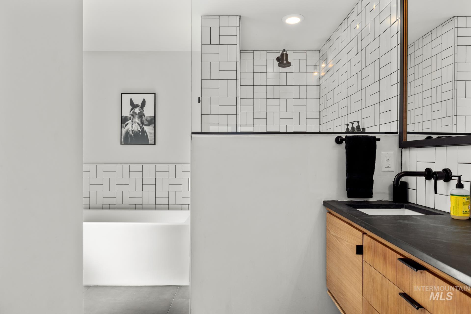 Full bath with tile walls, vanity, a freestanding bath, walk in shower, and tile patterned floors
