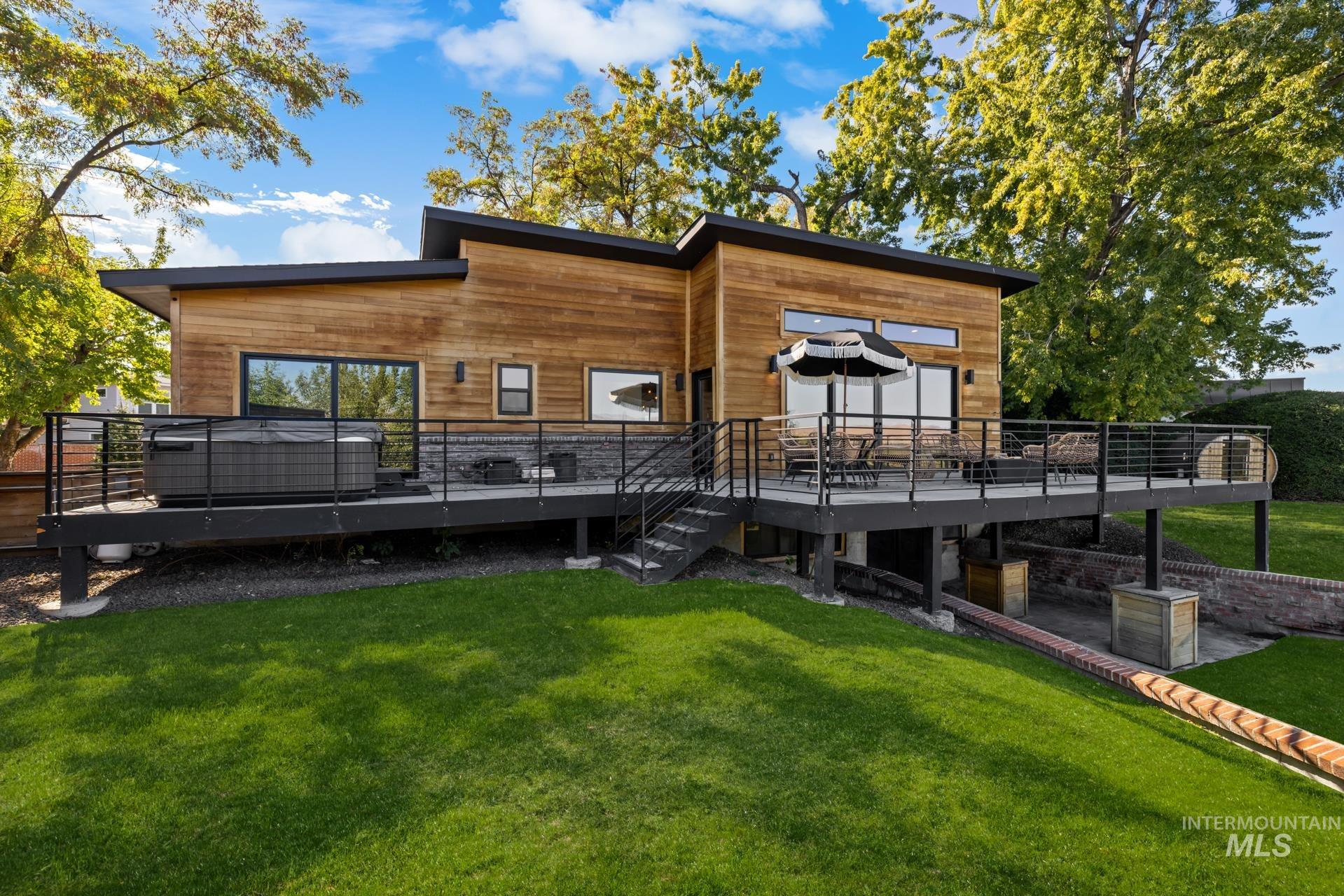 Back of property with a deck, a lawn, and stairway