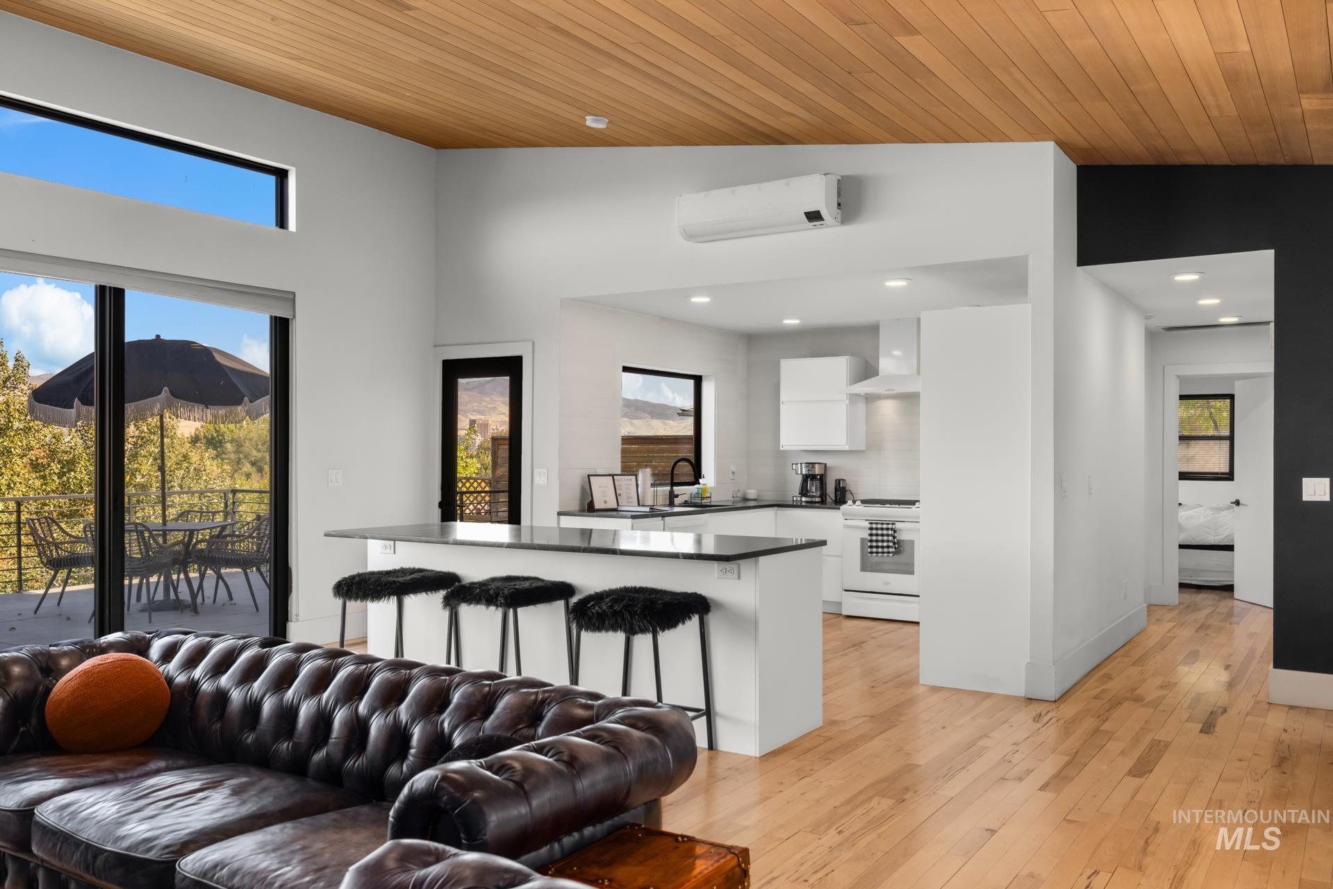 Living area featuring wooden ceiling, light wood-type flooring, a wall unit AC, lofted ceiling, and recessed lighting