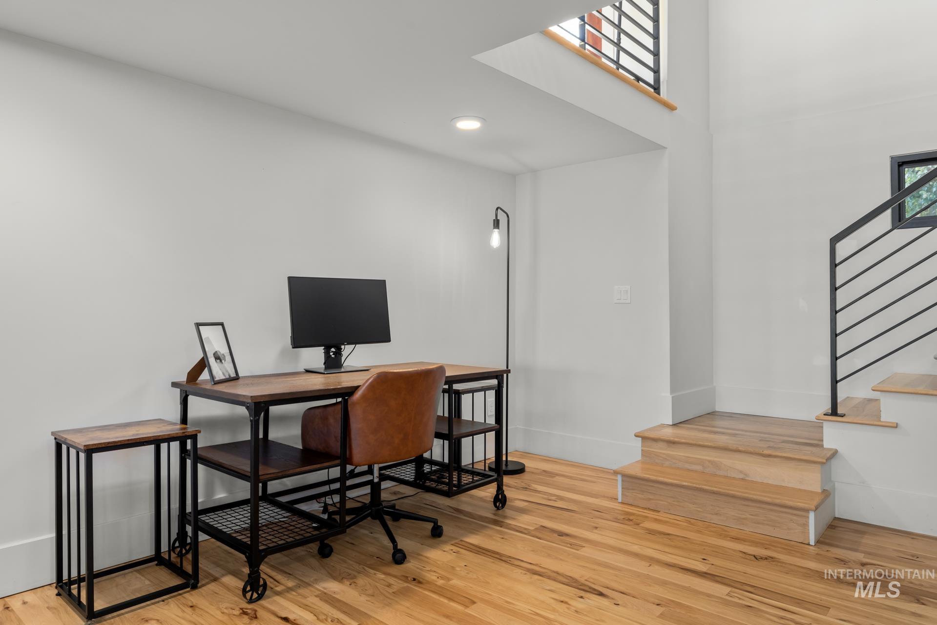 Home office featuring light wood-style flooring, a towering ceiling, and recessed lighting