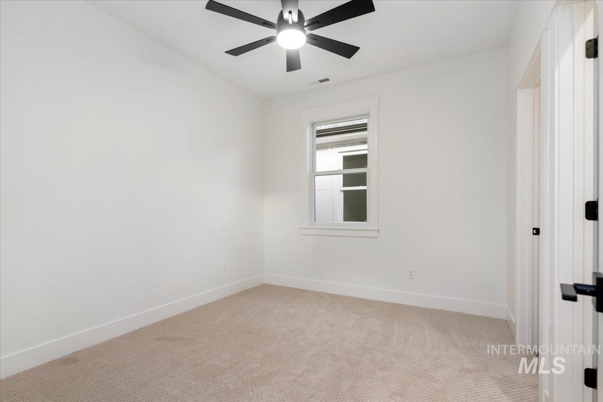 Empty room featuring light colored carpet and ceiling fan