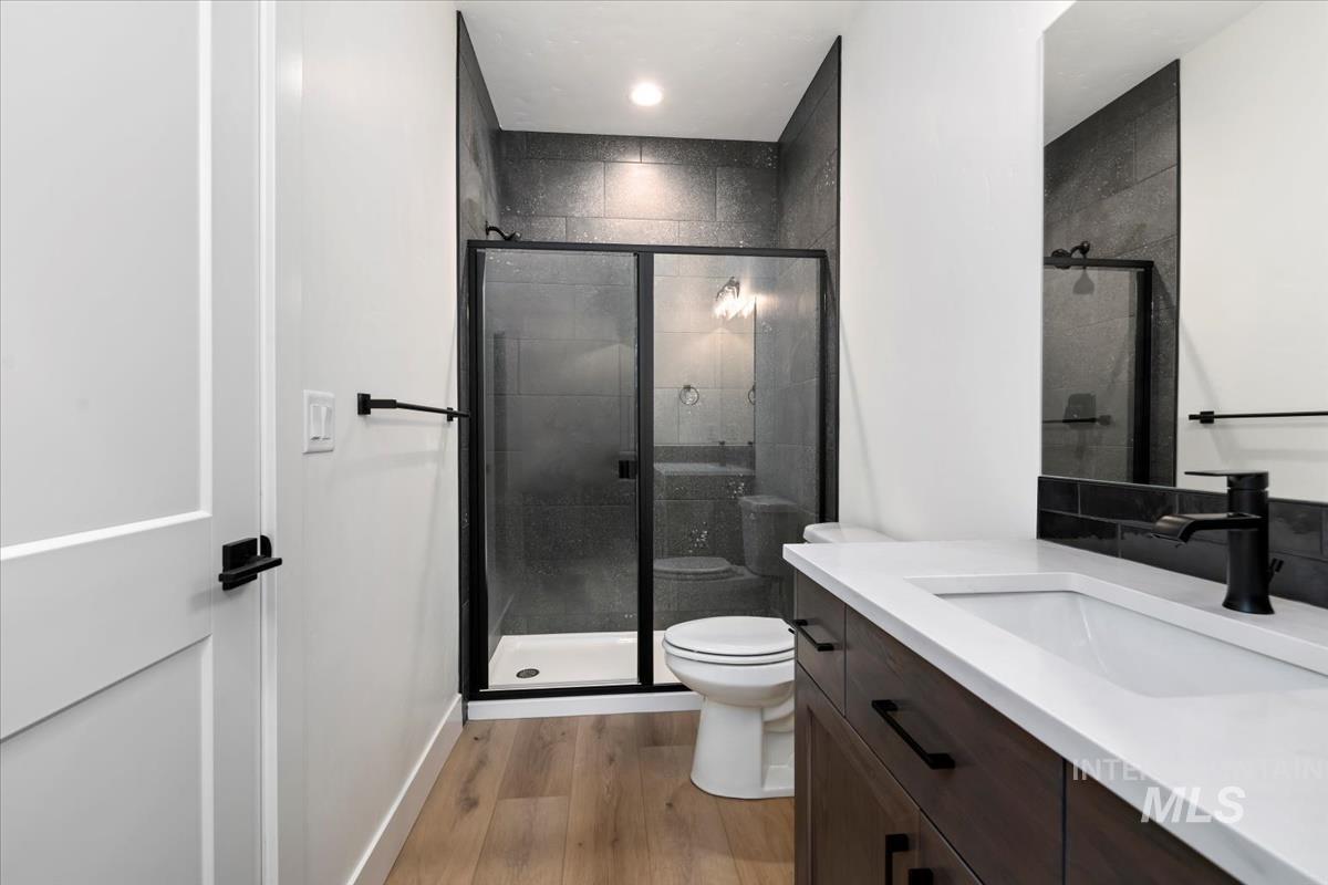Bathroom featuring light wood-style flooring, vanity, and a shower stall