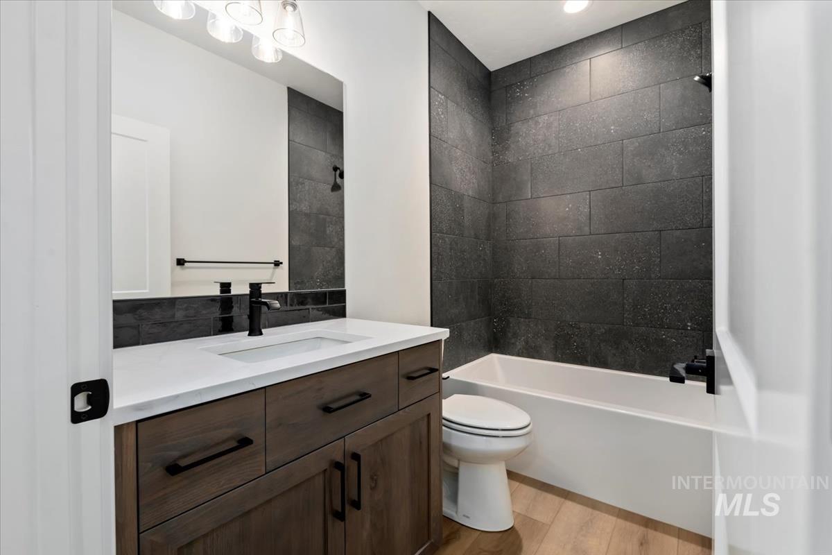 Full bathroom with light wood-style floors, vanity, and washtub / shower combination