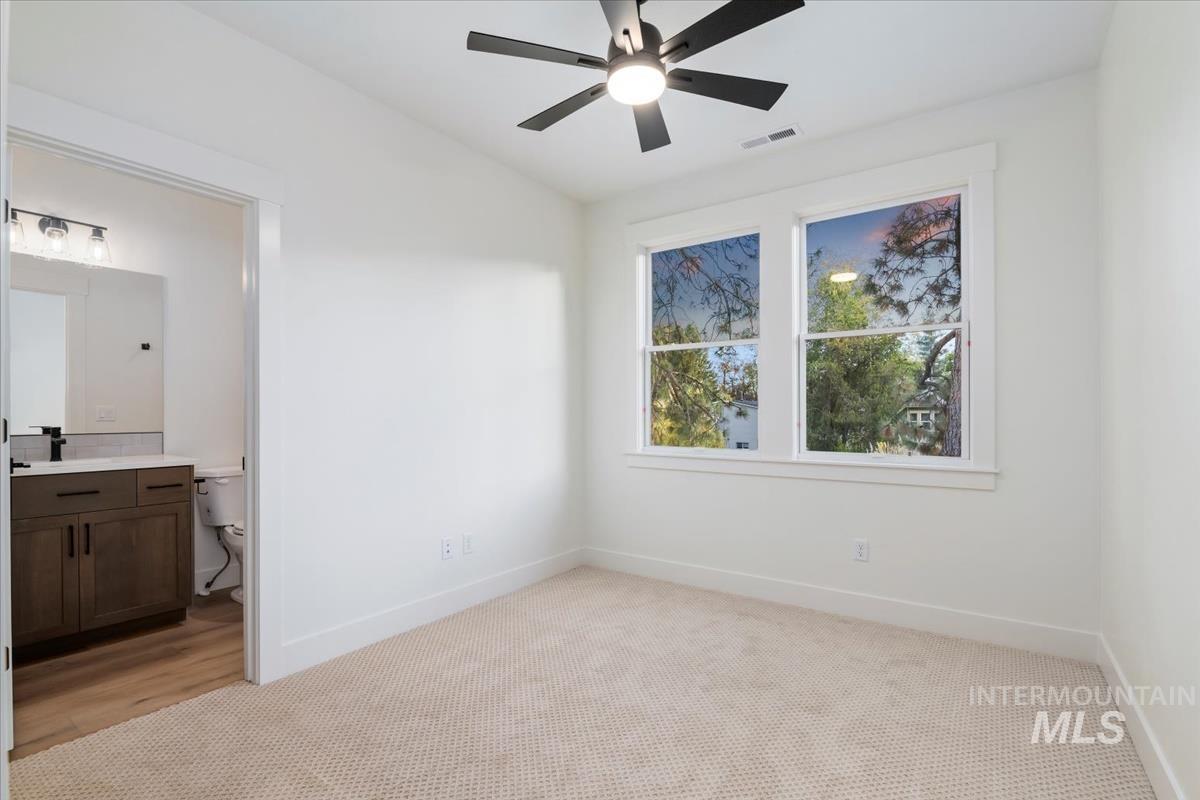 Unfurnished bedroom featuring light colored carpet, ceiling fan, and connected bathroom