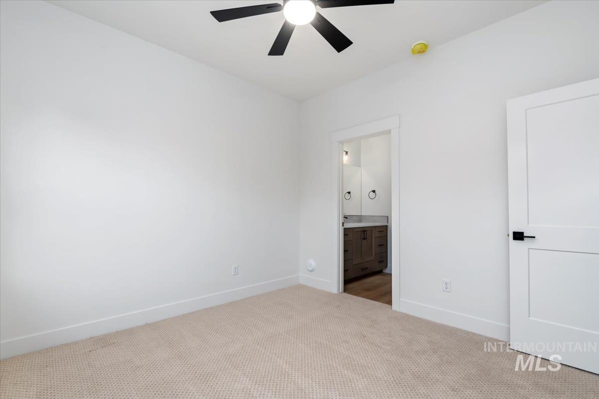 Unfurnished bedroom featuring carpet floors, connected bathroom, and a ceiling fan