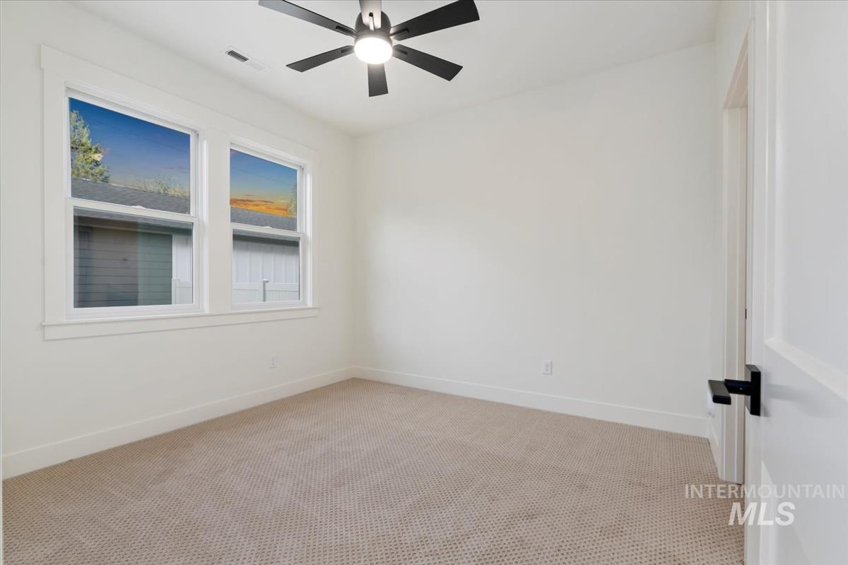 Carpeted spare room with baseboards and ceiling fan