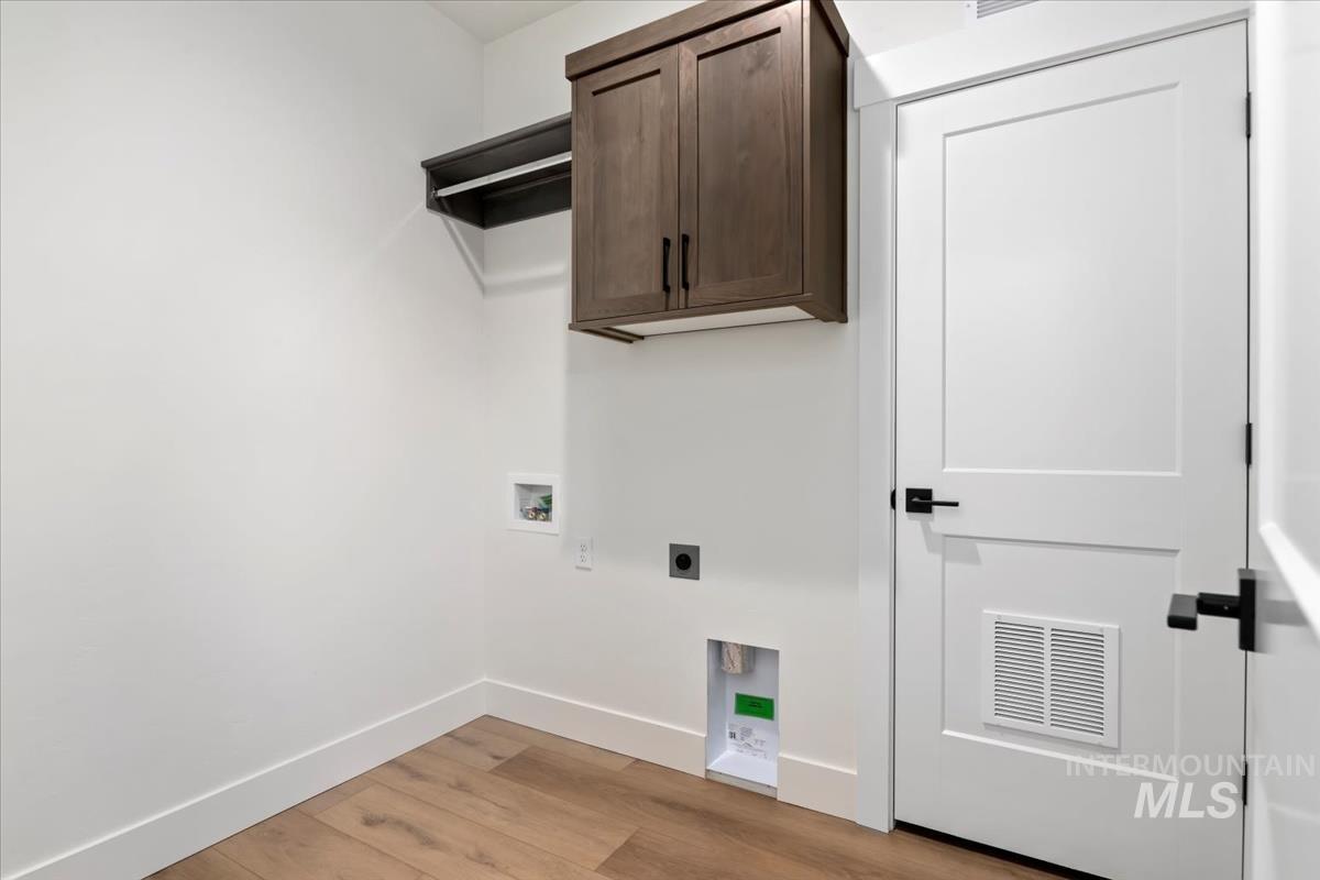 Laundry room with light wood-style flooring, hookup for an electric dryer, washer hookup, and cabinet space
