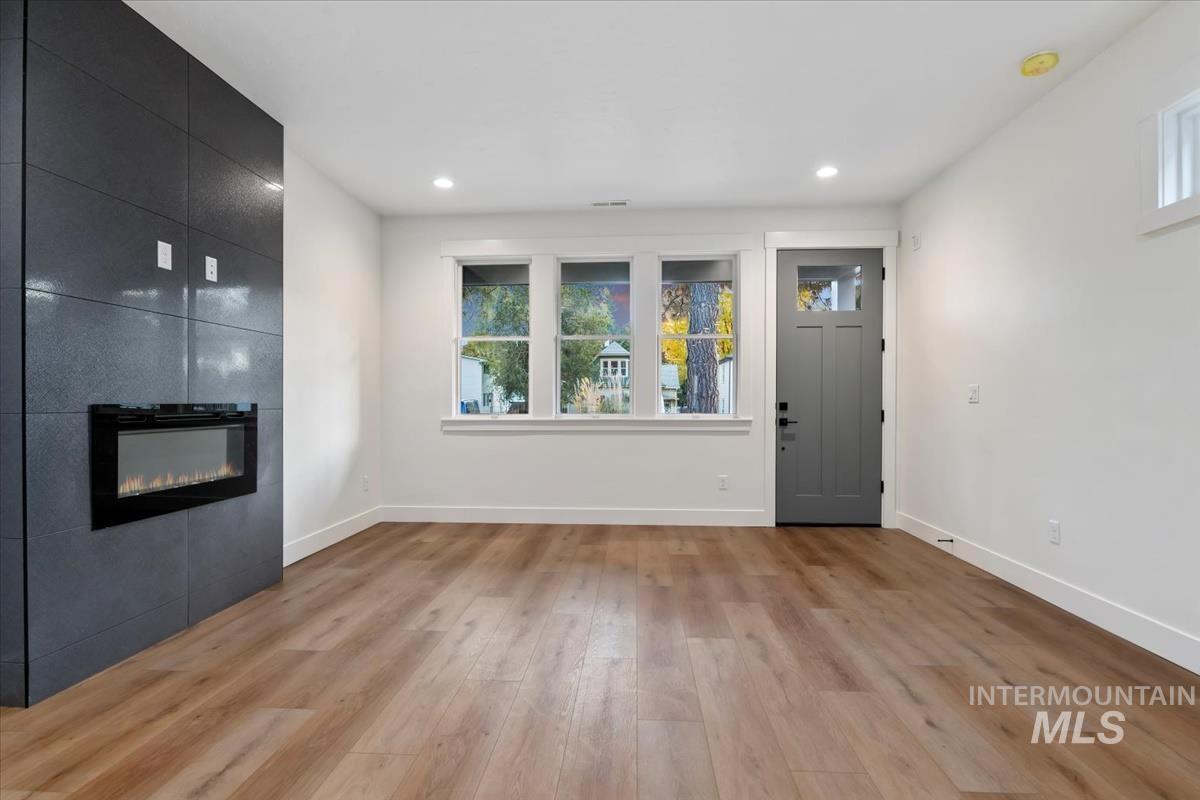 Foyer entrance featuring healthy amount of natural light, light wood finished floors, recessed lighting, and a large fireplace