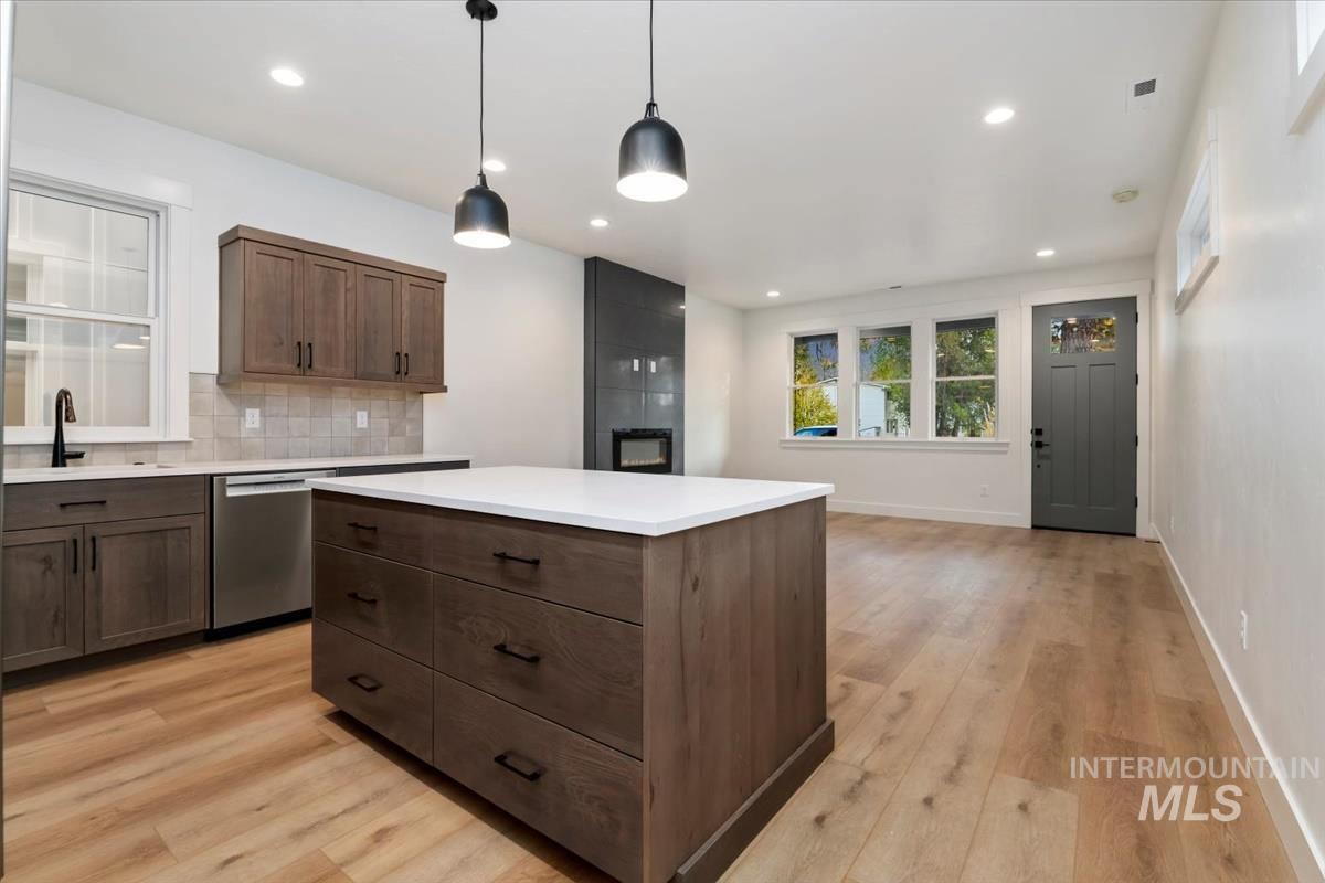 Kitchen featuring pendant lighting, backsplash, a kitchen island, dishwasher, and recessed lighting