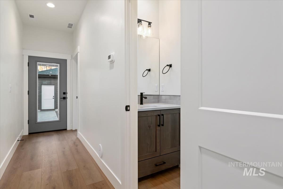 Half bath with light wood-style floors, vanity, and recessed lighting