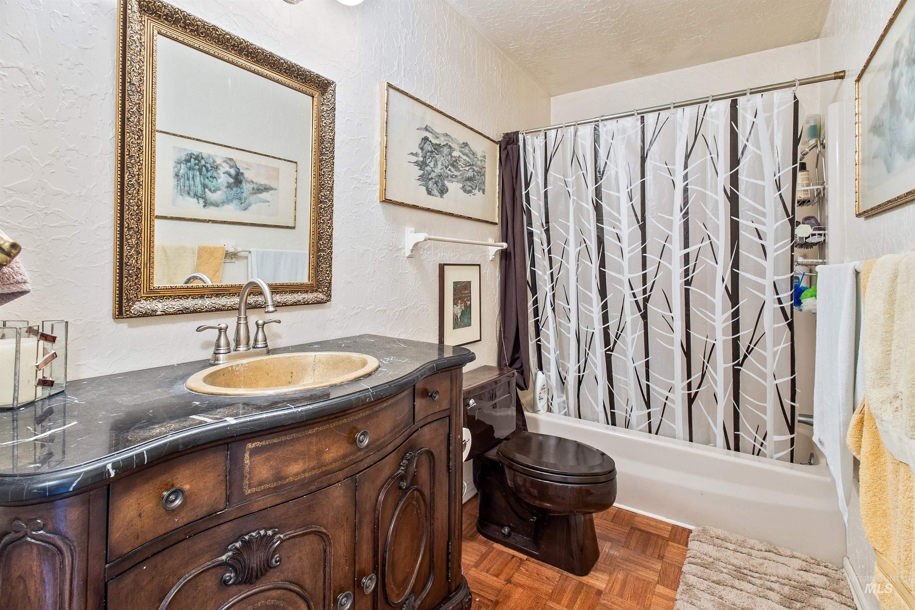 Full bath featuring a textured wall, shower / bath combo, vanity, and a textured ceiling