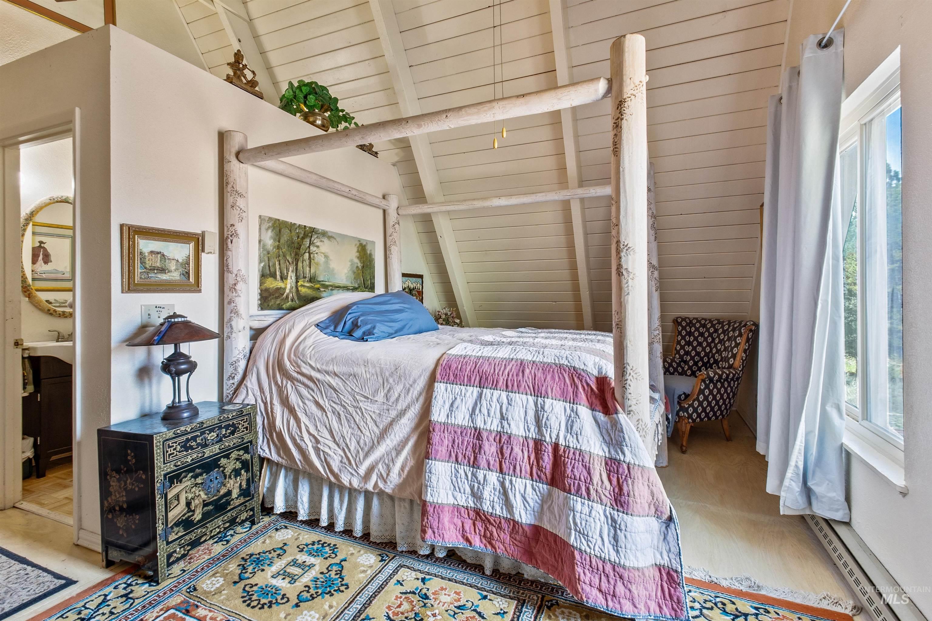 Bedroom featuring vaulted ceiling, a baseboard radiator, and wooden ceiling