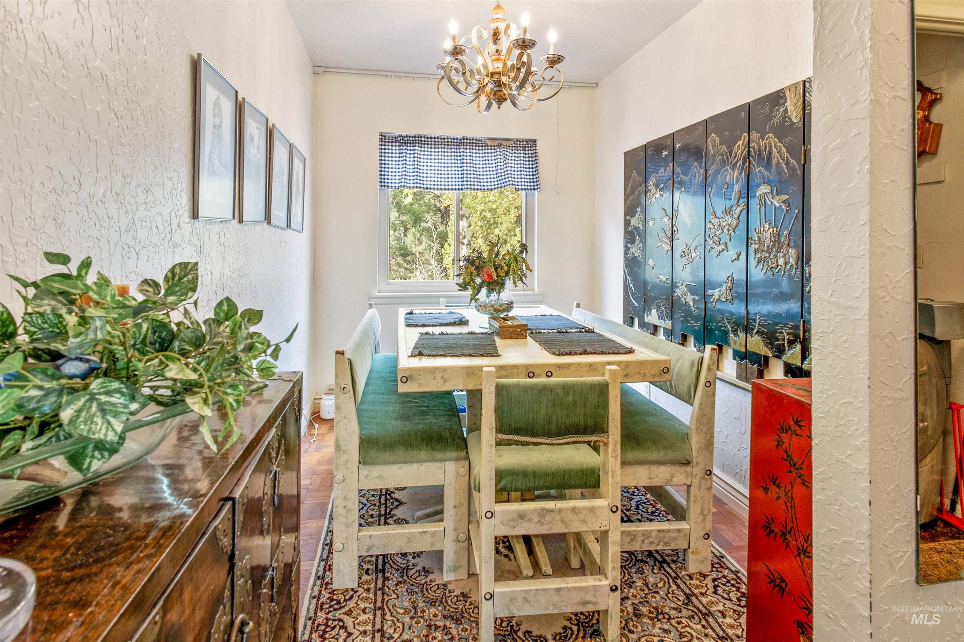 Dining space with a textured wall, wood finished floors, and a chandelier
