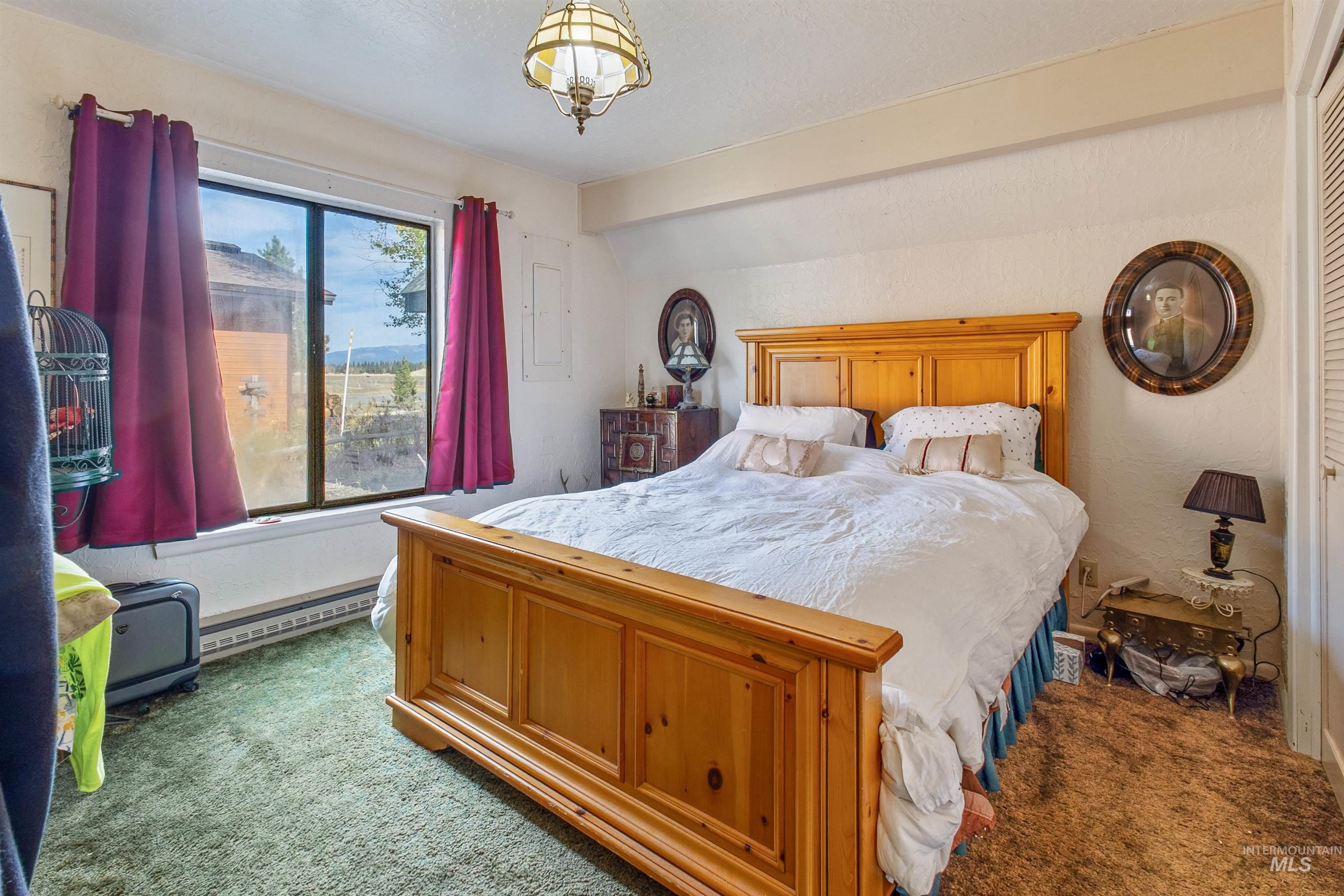 Carpeted bedroom with baseboard heating and beam ceiling