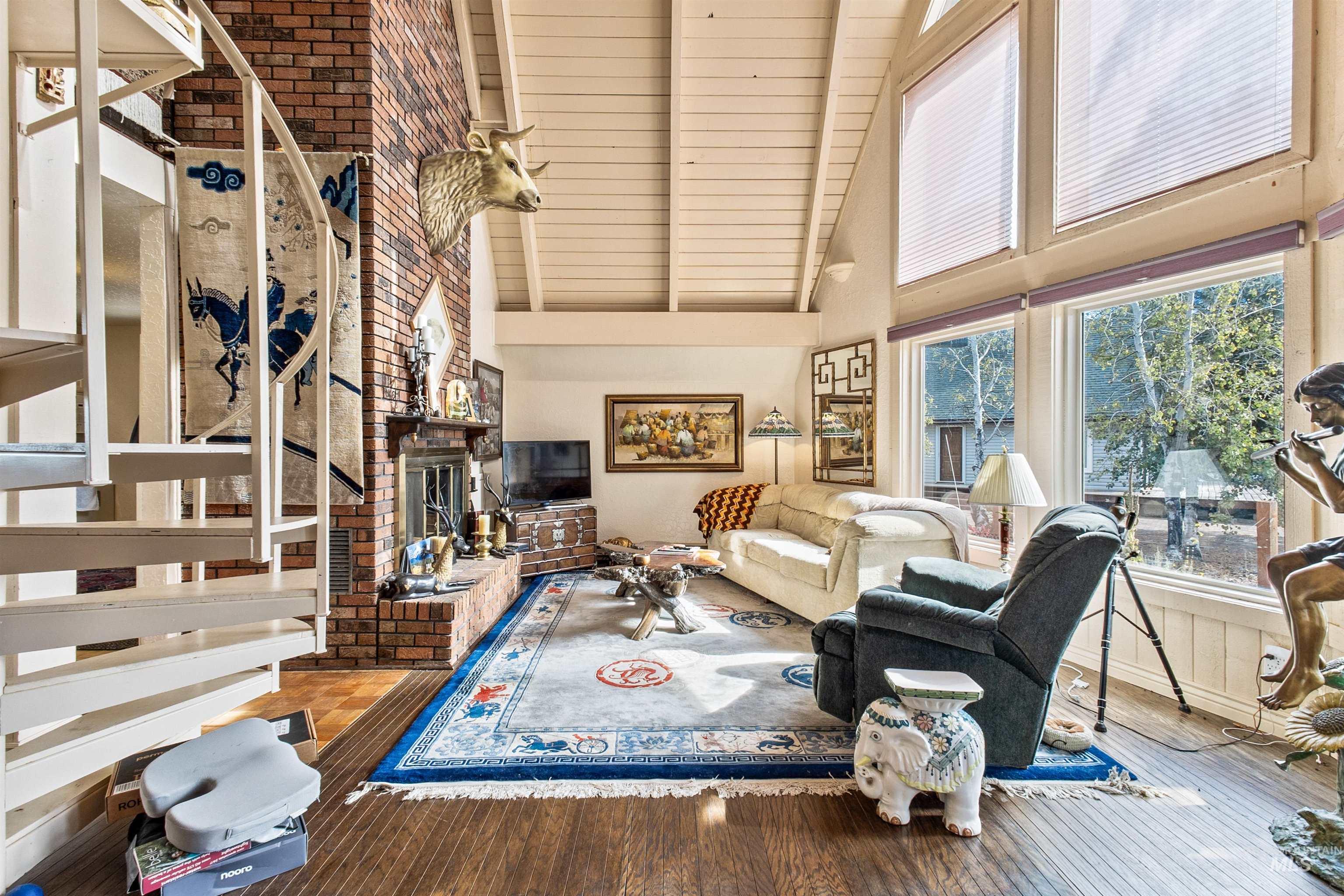 Living area with a brick fireplace, high vaulted ceiling, hardwood / wood-style floors, and a wood ceiling with exposed beams