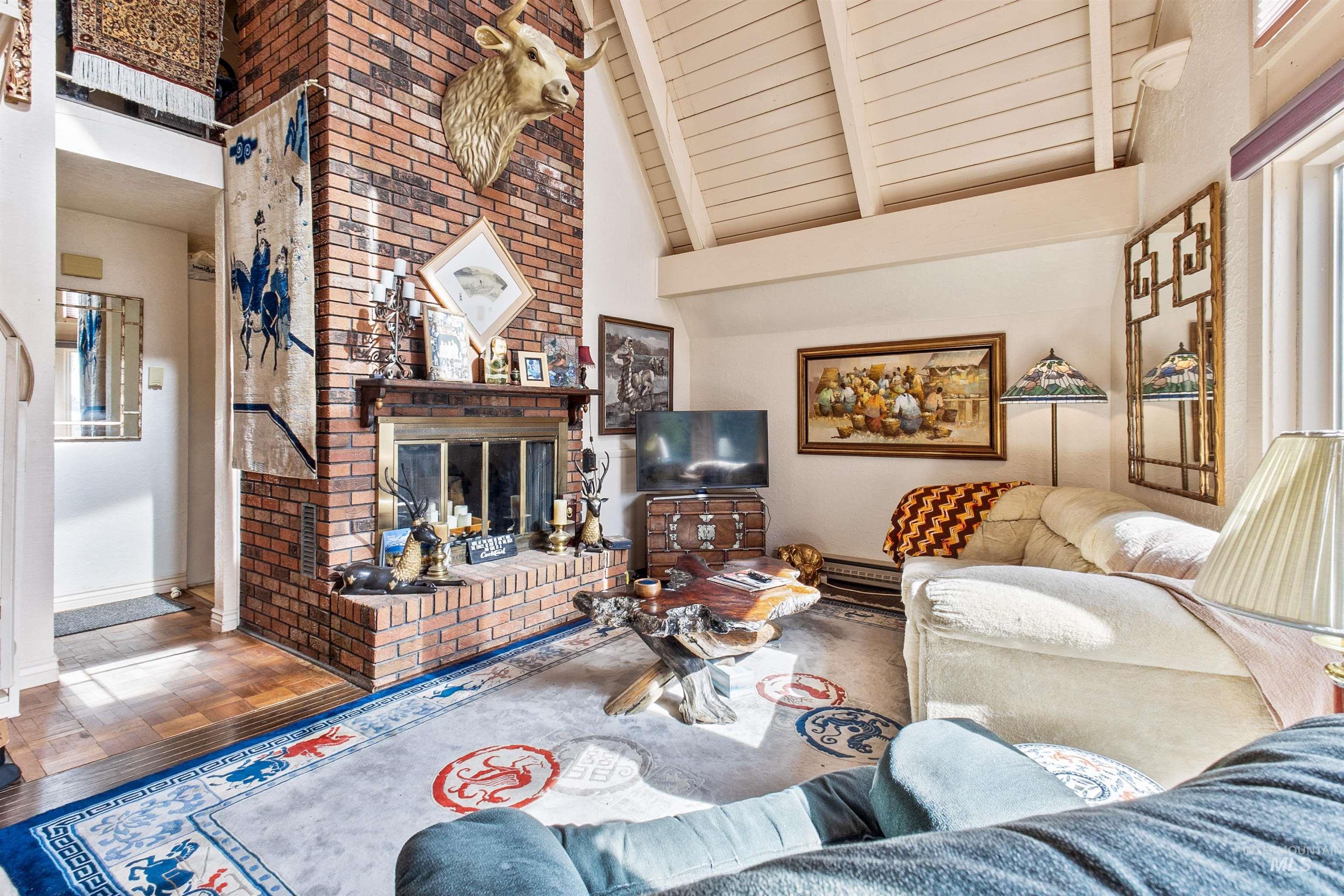 Family room with high vaulted ceiling, a fireplace, wood finished floors, and a wood ceiling with exposed beams