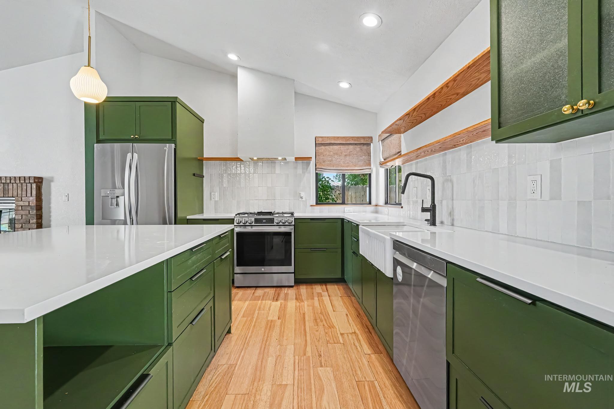 Kitchen featuring green cabinetry, light-tone wood-finish flooring, quartz countertops, and a white subway tile backsplash