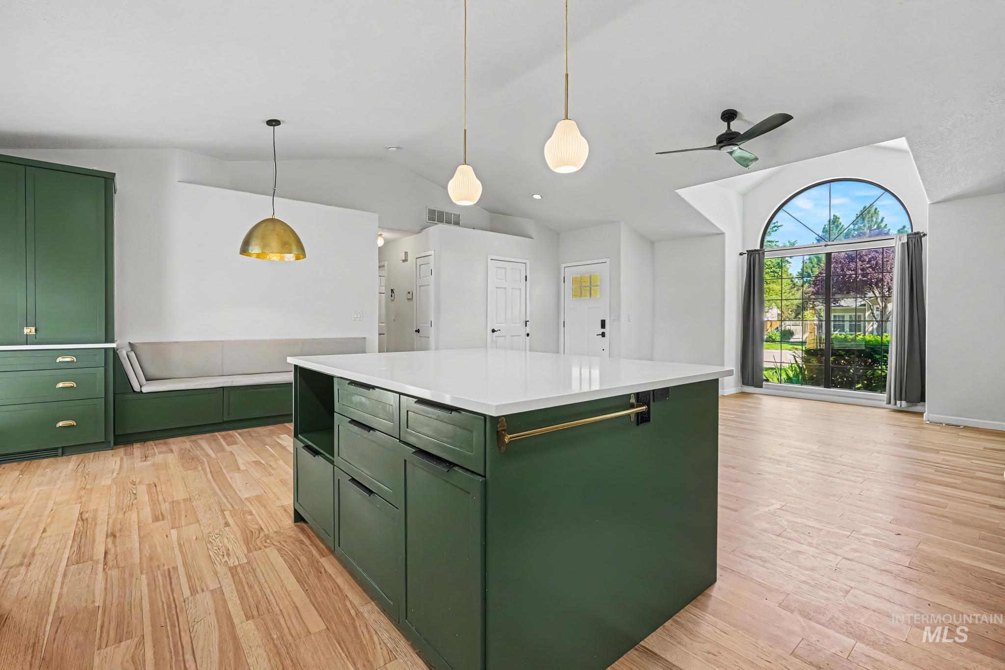 Kitchen island with quartz countertop, rich green cabinetry, and brass hardware