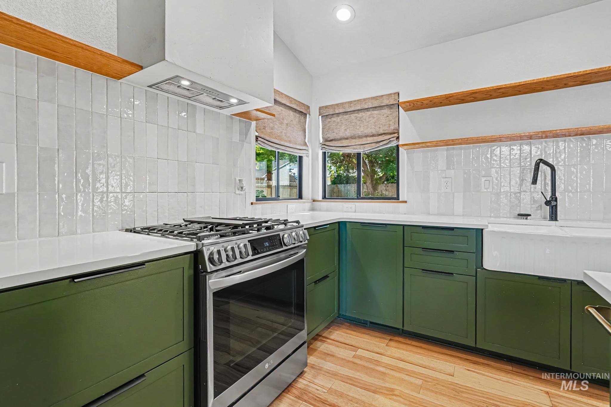 Modern kitchen featuring forest green cabinetry, white countertops, and a full tile backsplash