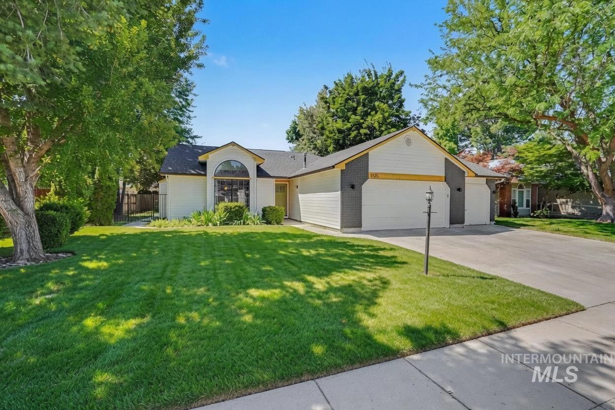 Inviting single-story residence featuring a prominent arched window, two-car garage, and a concrete driveway