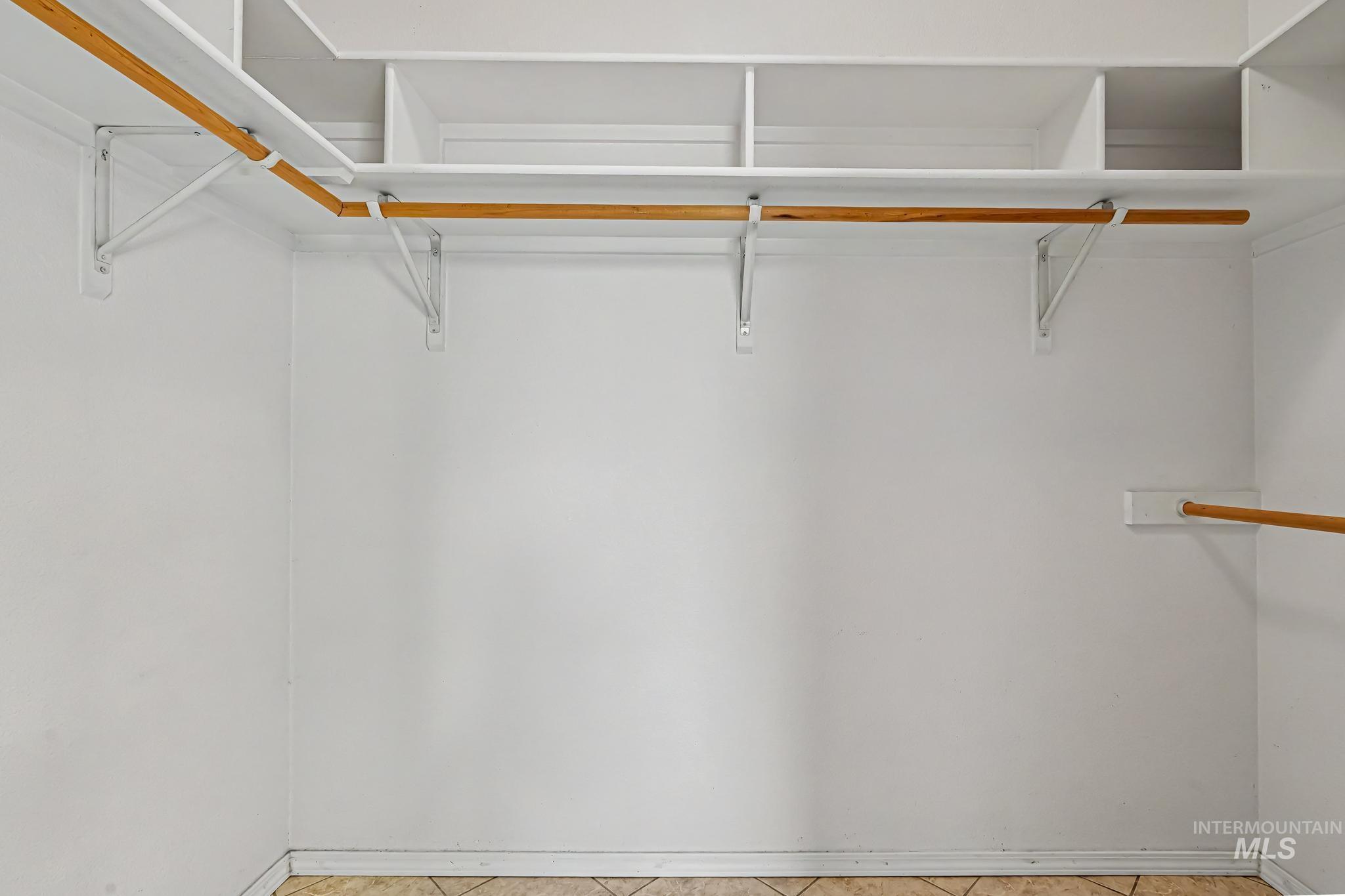 Built-in closet organization system featuring white shelving and natural wood hanging rods
