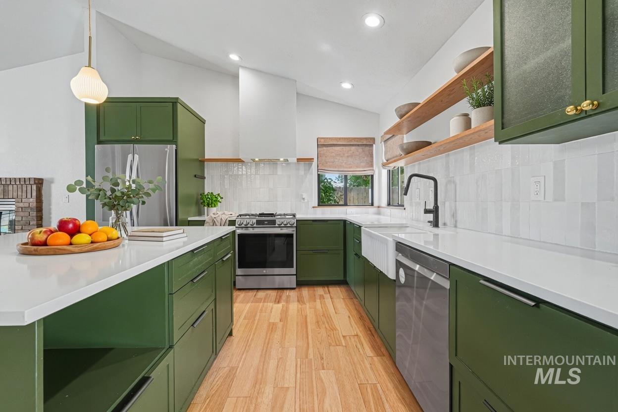 Renovated kitchen featuring a vaulted ceiling, wood-finish flooring and quartz counters. *Virtually Staged photo*