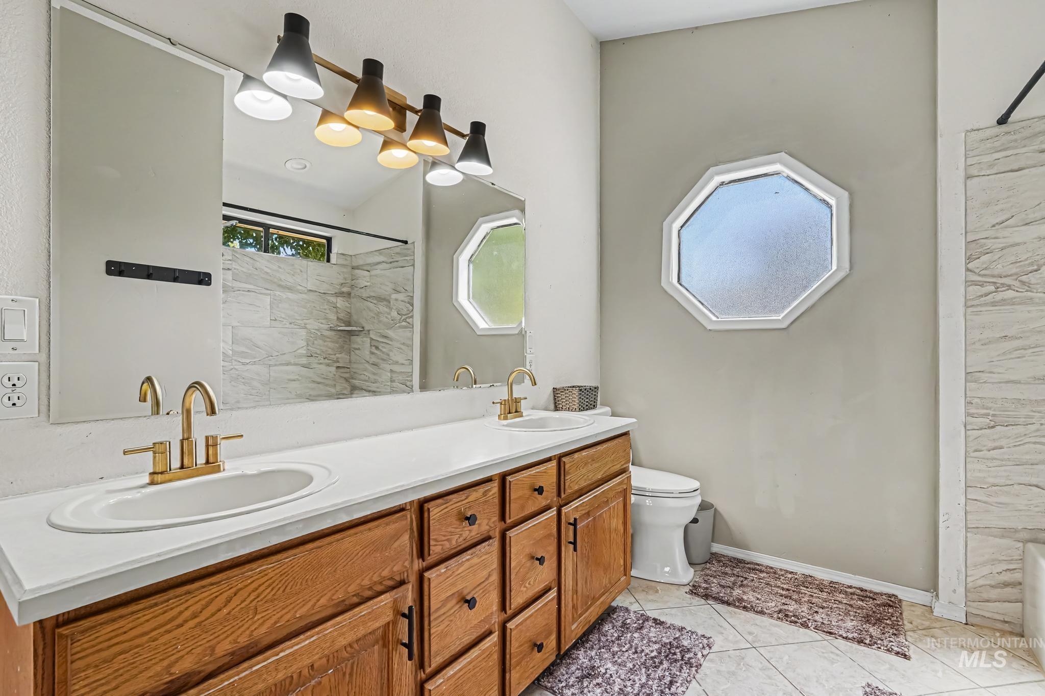 Bathroom featuring a dual-sink vanity with wood cabinetry, white countertops, and gold-finish fixtures