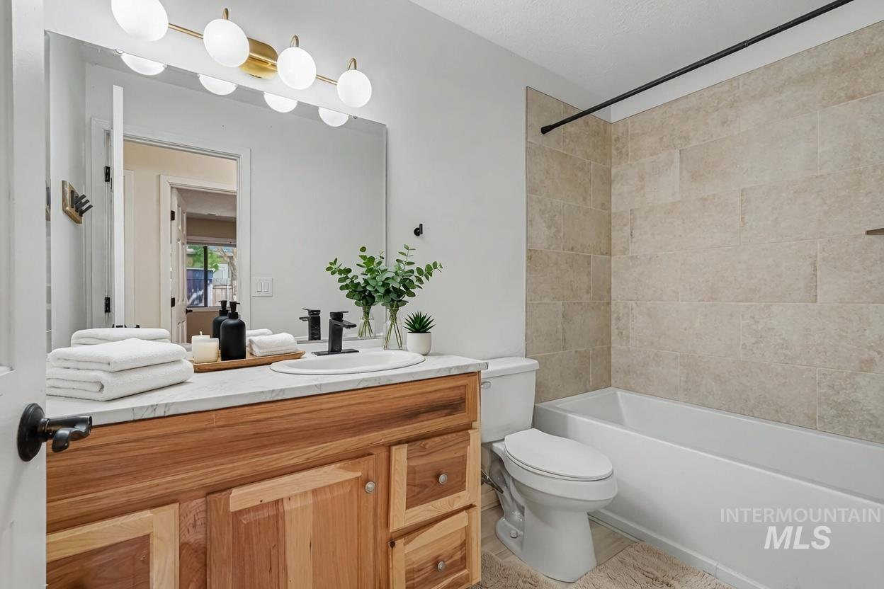 Bathroom featuring a natural wood-finish vanity, white countertop, and a large mirror. *Virtually Staged photo*