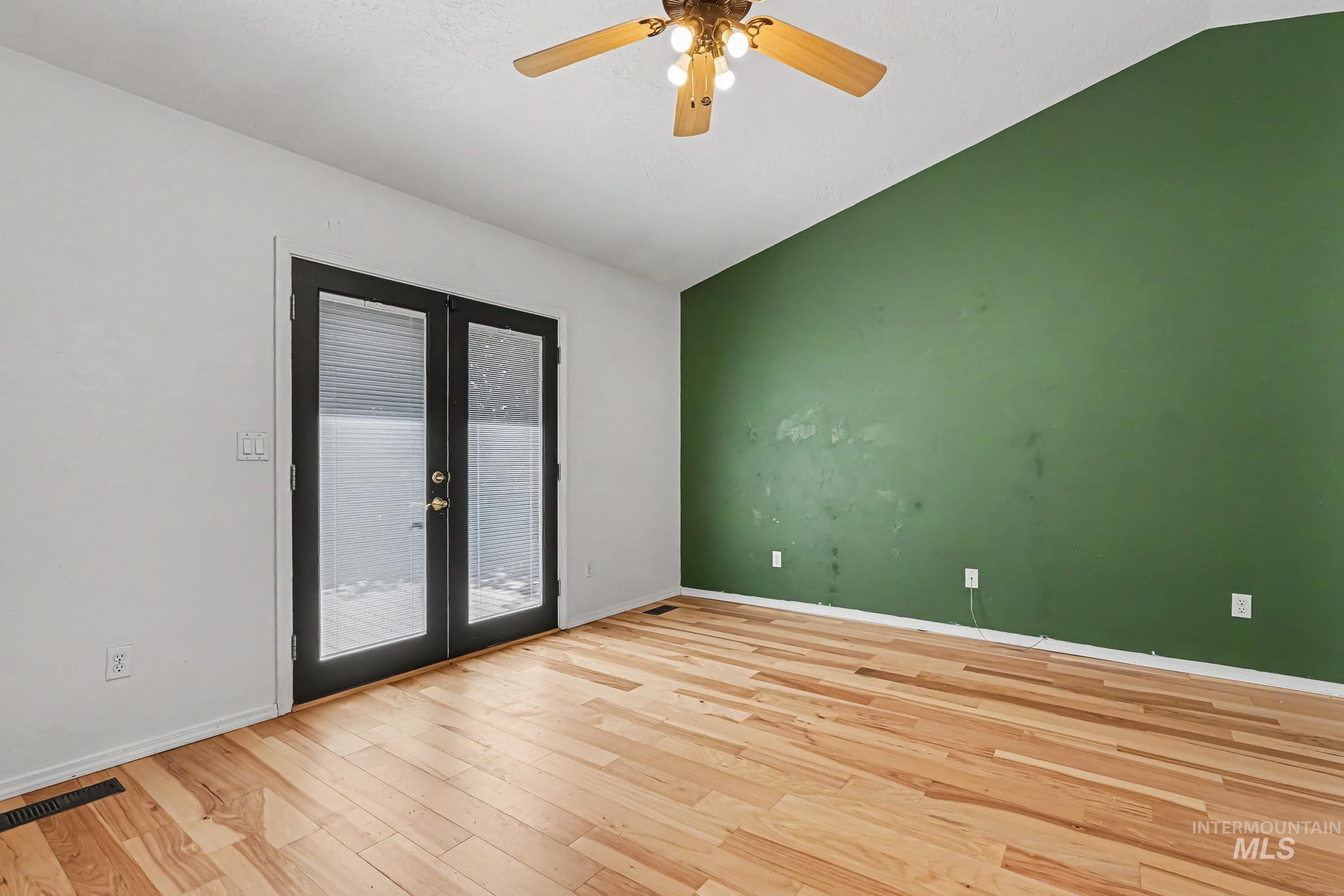 Room featuring hardwood flooring and a vaulted ceiling with a ceiling fan