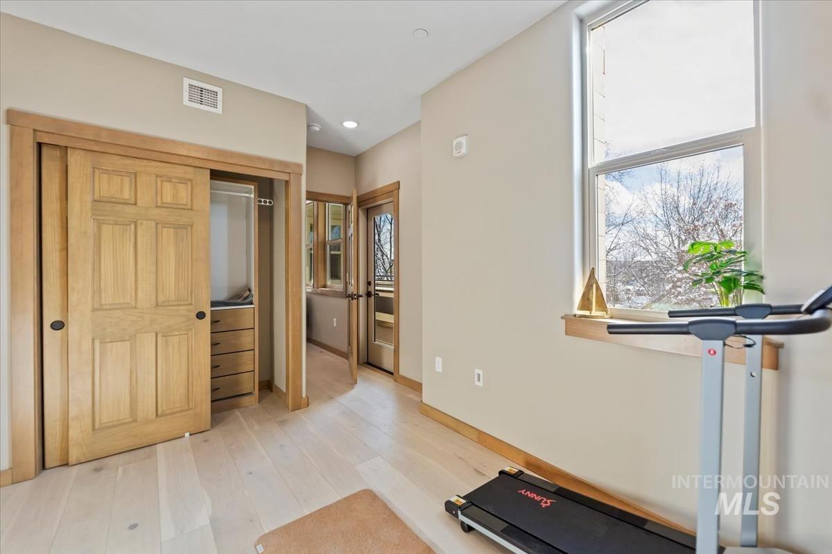 Workout room with light wood finished floors and recessed lighting