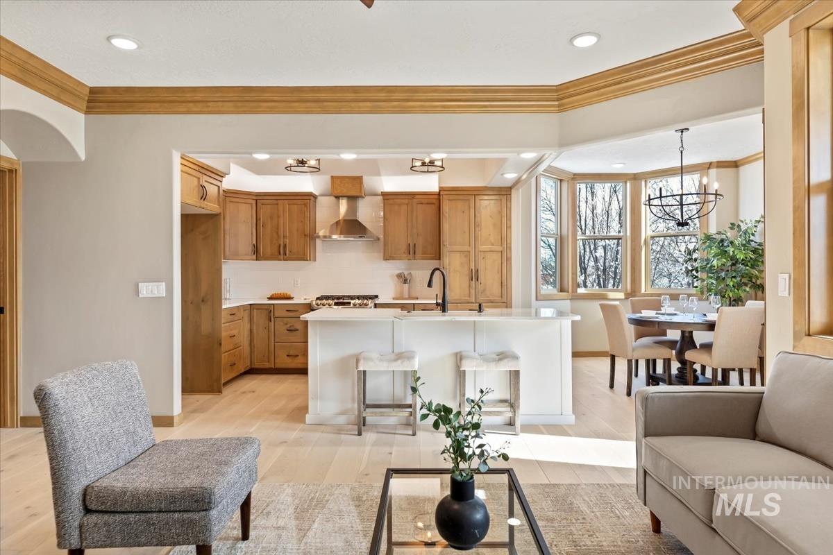 Living room featuring ornamental molding, a chandelier, light wood-style flooring, and recessed lighting