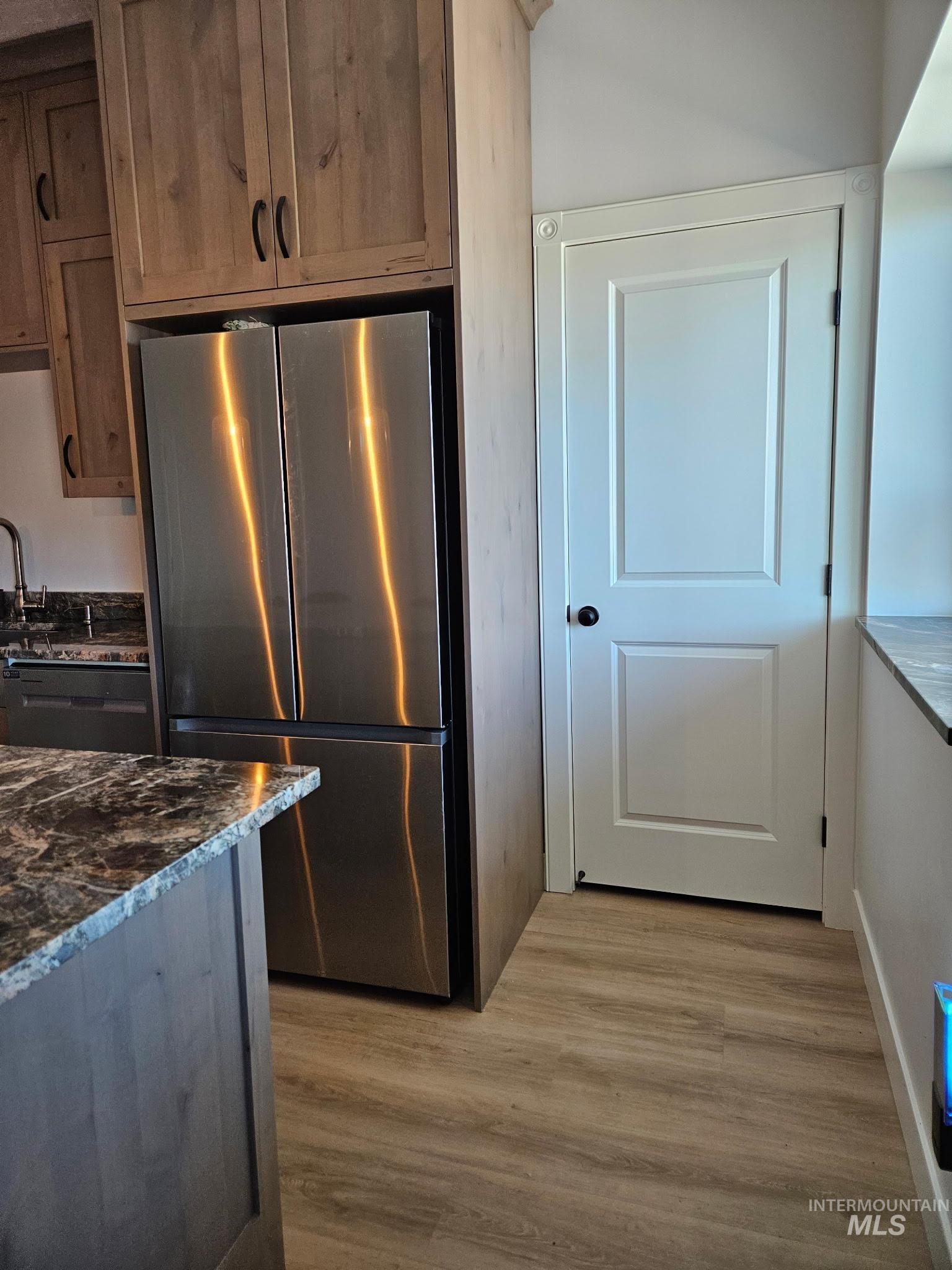 Kitchen with freestanding refrigerator, LVP floors, granite counters, and dishwasher
