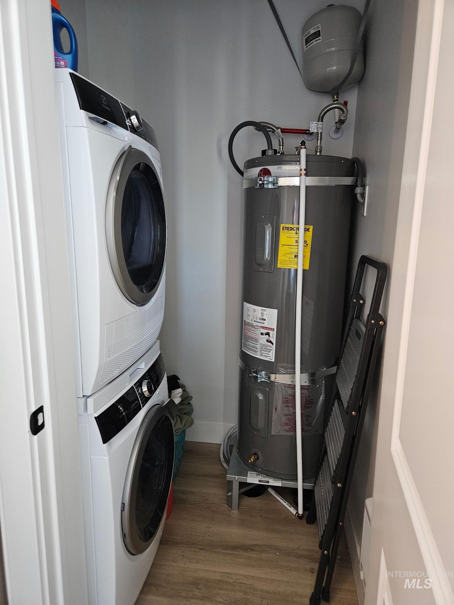 Laundry/Utility room with LVP floors, secured water heater, and stacked washer and dryer
