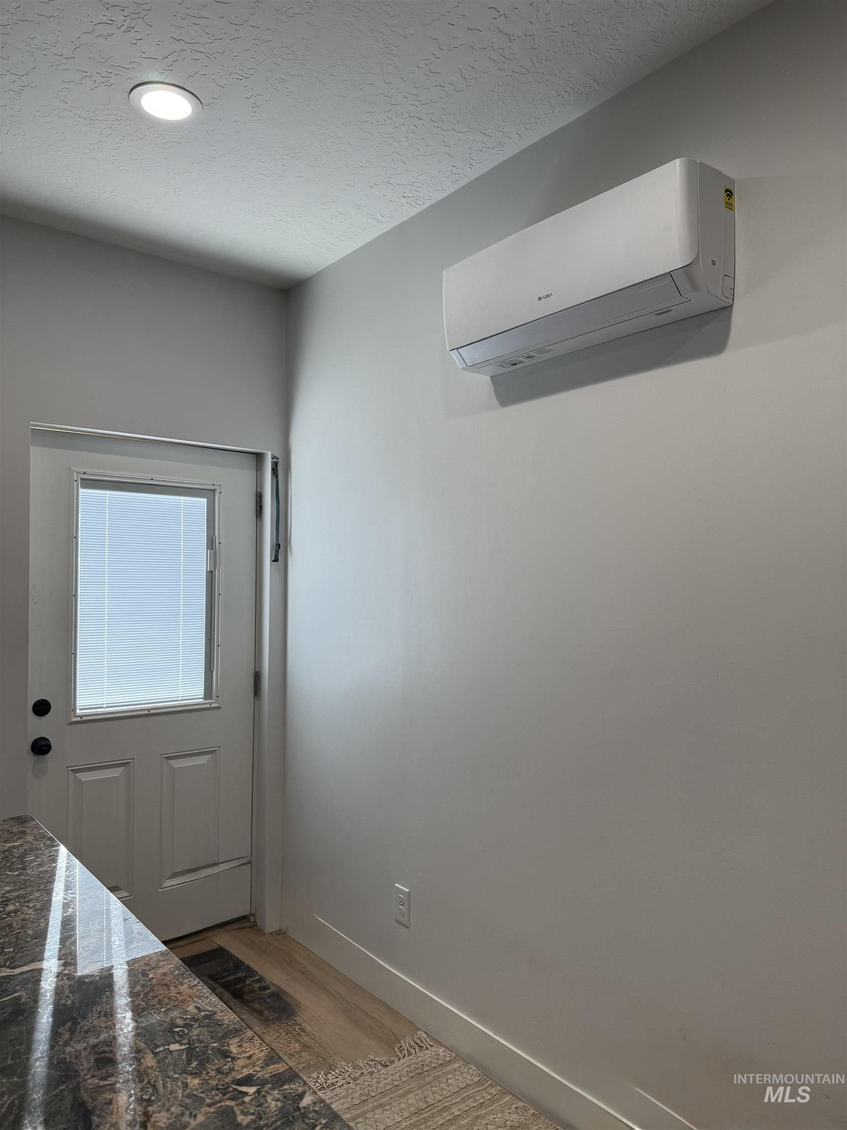 Doorway to outside with a textured ceiling, a wall mounted mini-split, LVP floors, and recessed lighting