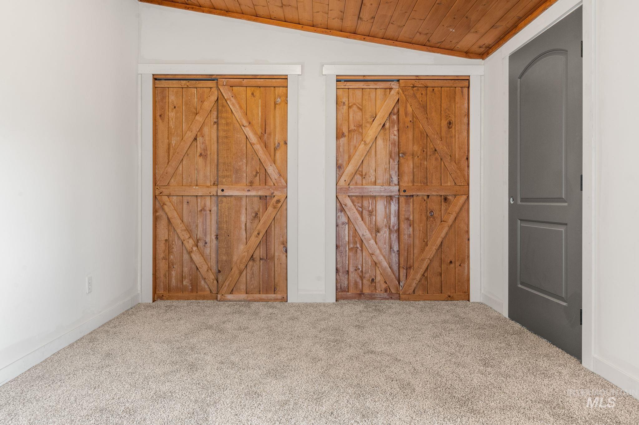 Interior space featuring vaulted ceiling, carpet flooring, and wood ceiling