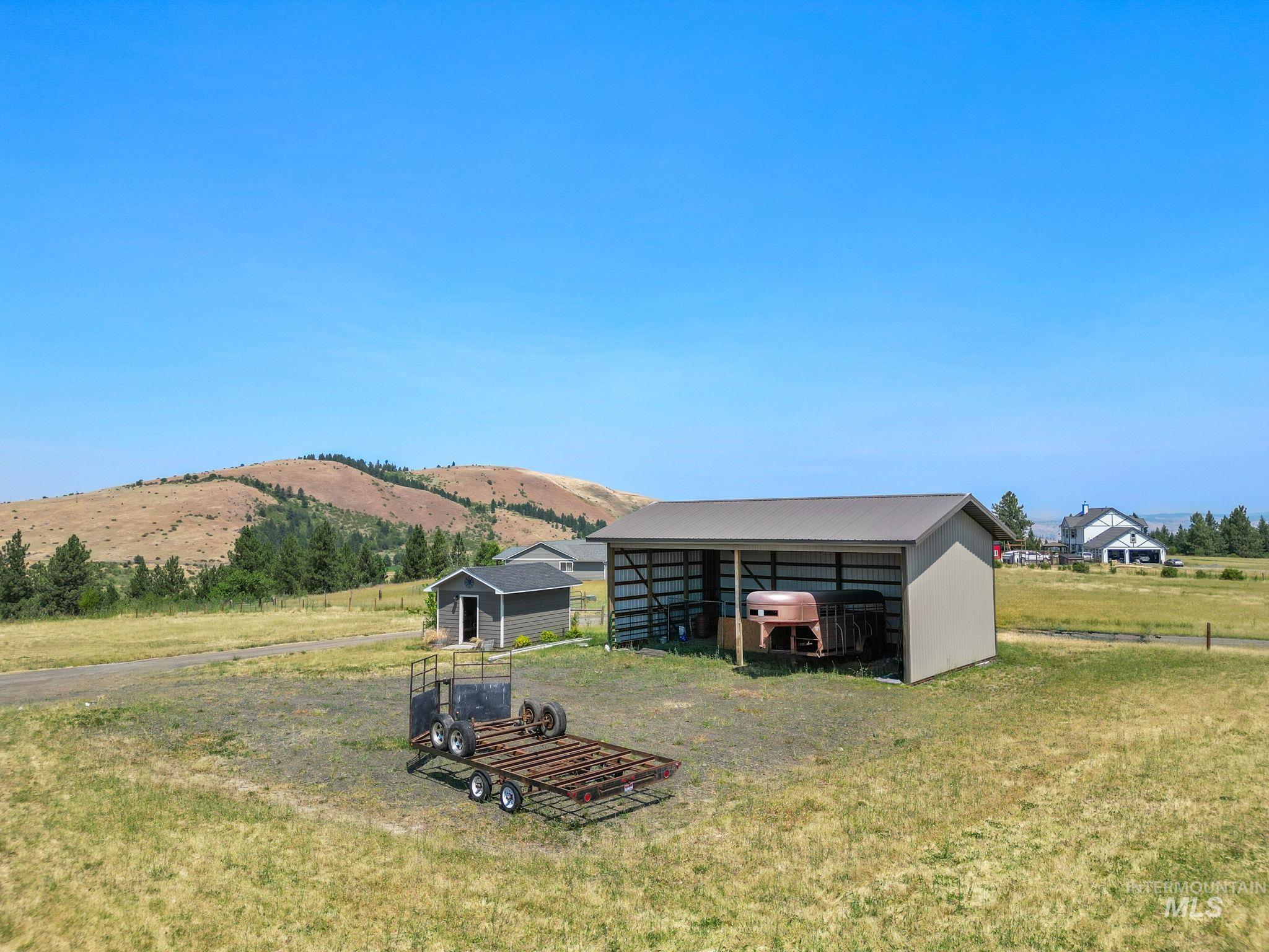 Rear view of house featuring an outbuilding, a pole building, a rural view, and a yard