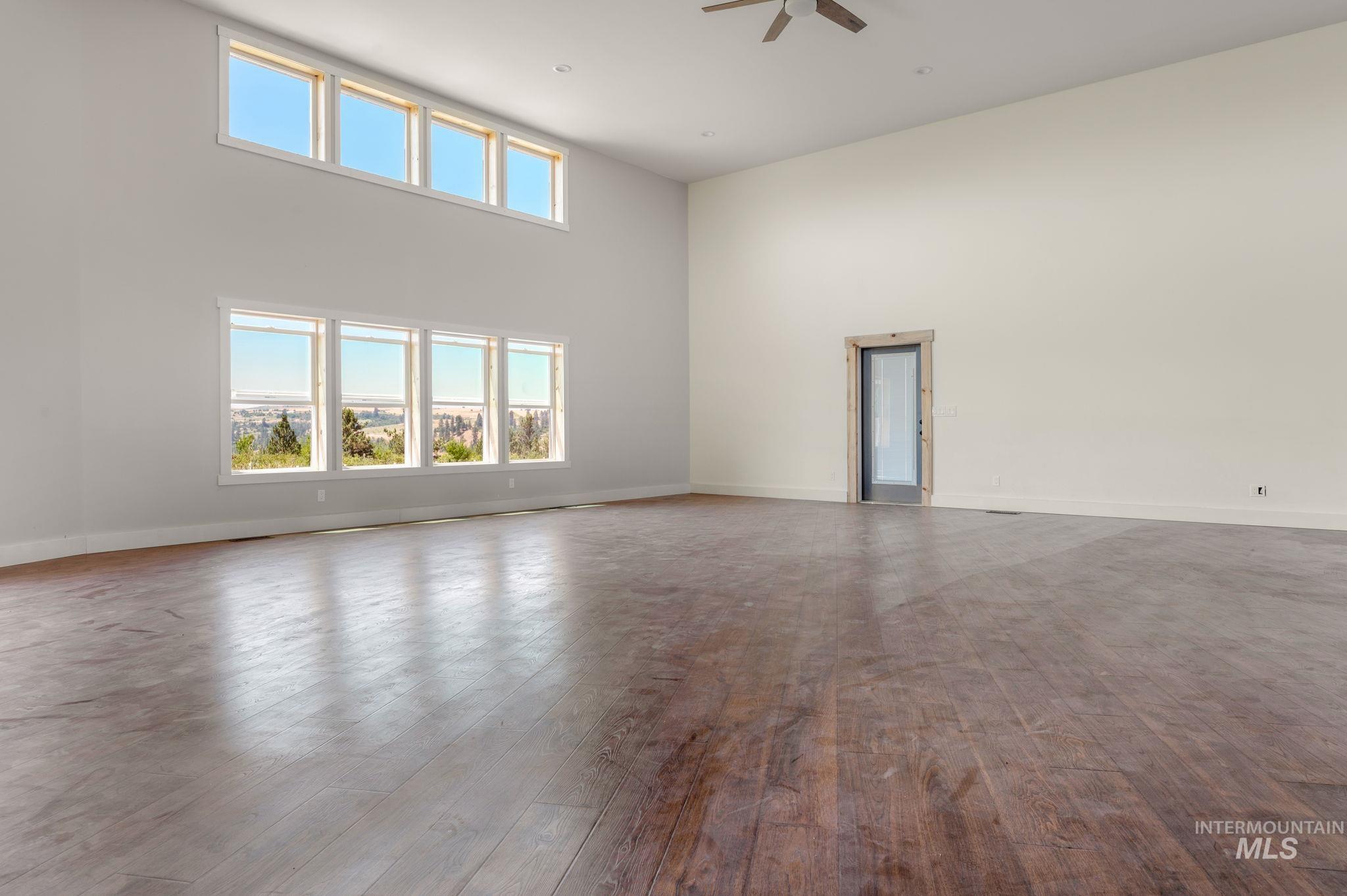 Unfurnished room with a towering ceiling, hardwood / wood-style floors, and a ceiling fan