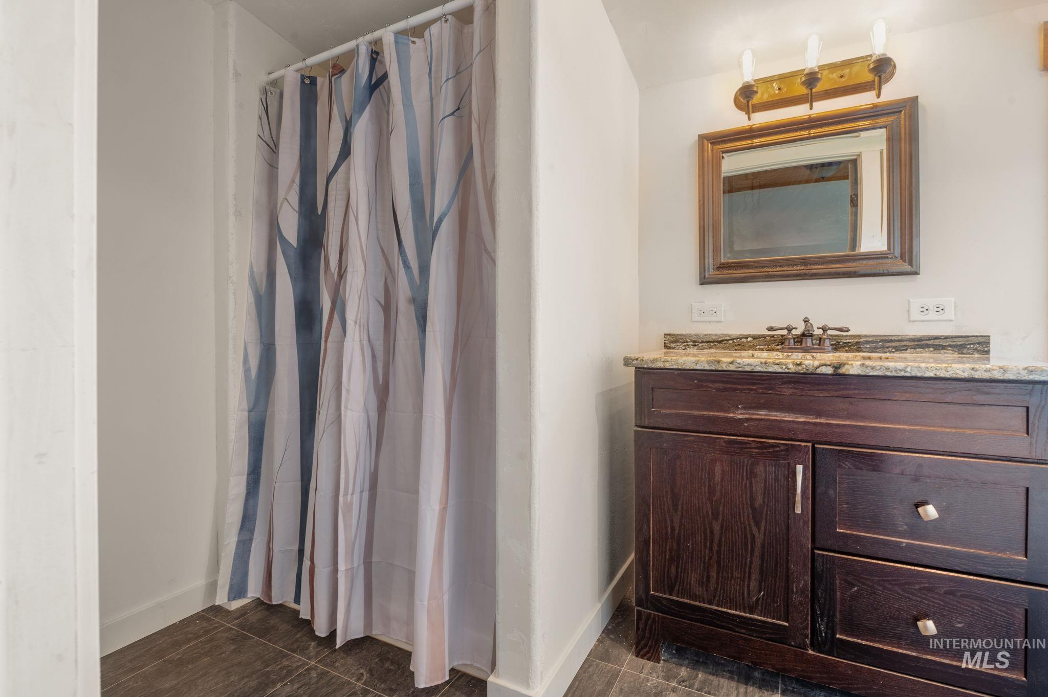 Bathroom featuring vanity, a shower with curtain, and dark tile patterned flooring