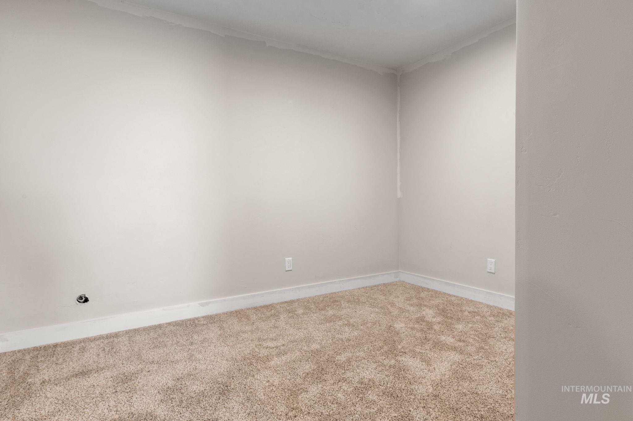 Carpeted spare room featuring baseboards