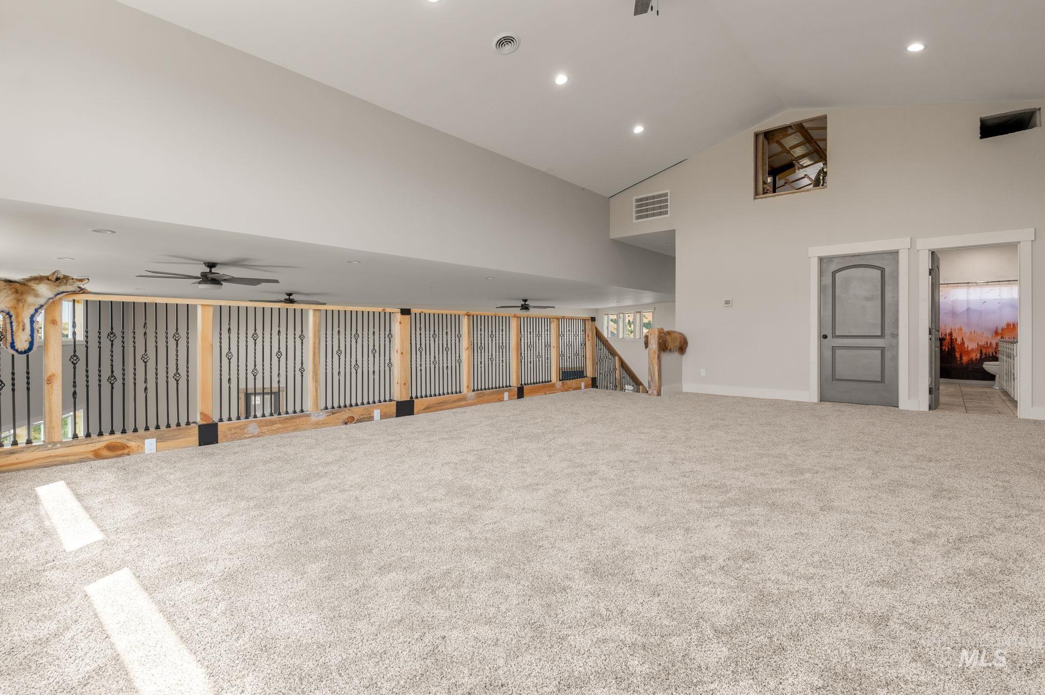 Carpeted empty room featuring high vaulted ceiling and recessed lighting