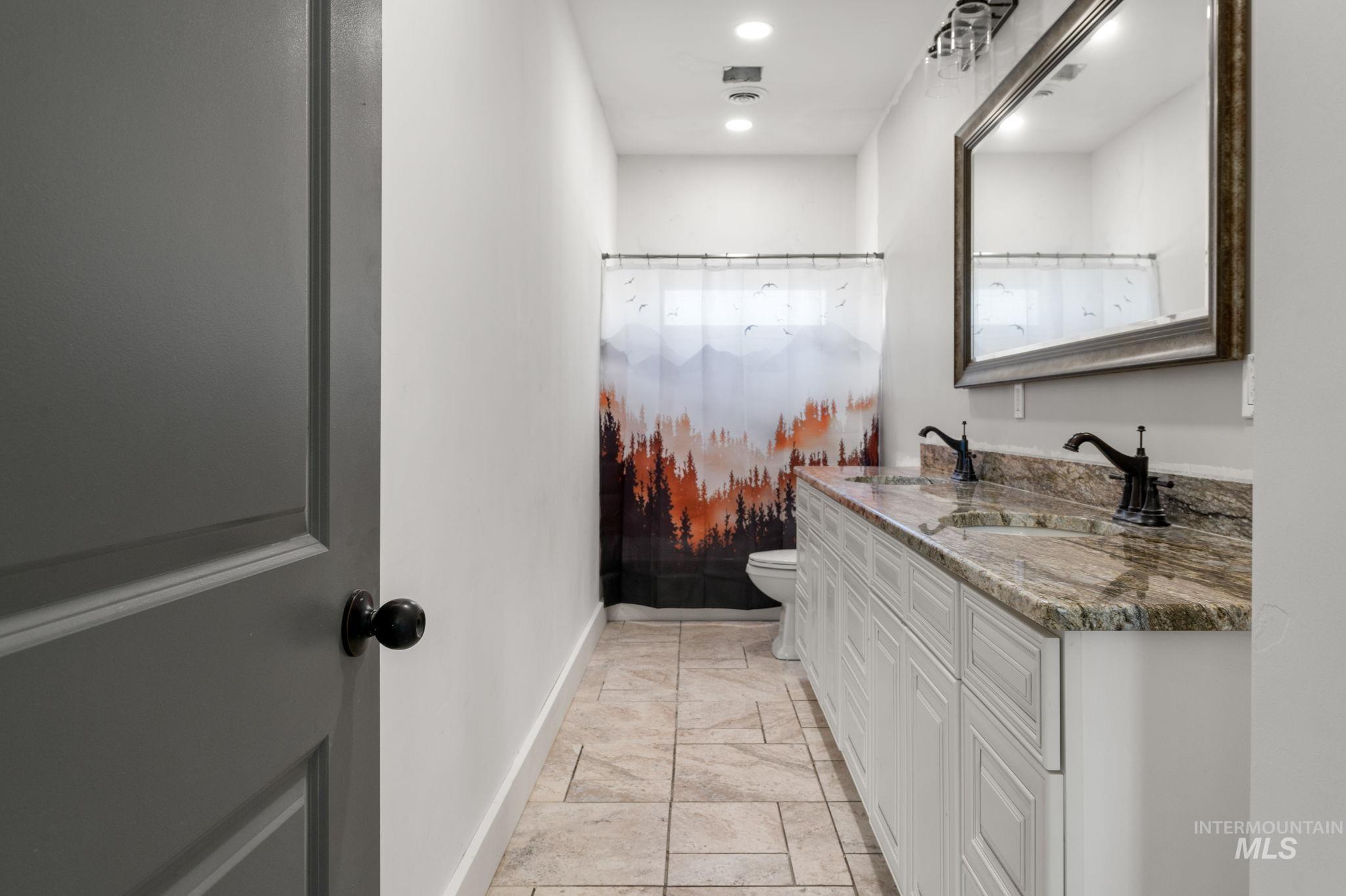 Full bathroom with double vanity, curtained shower, and recessed lighting